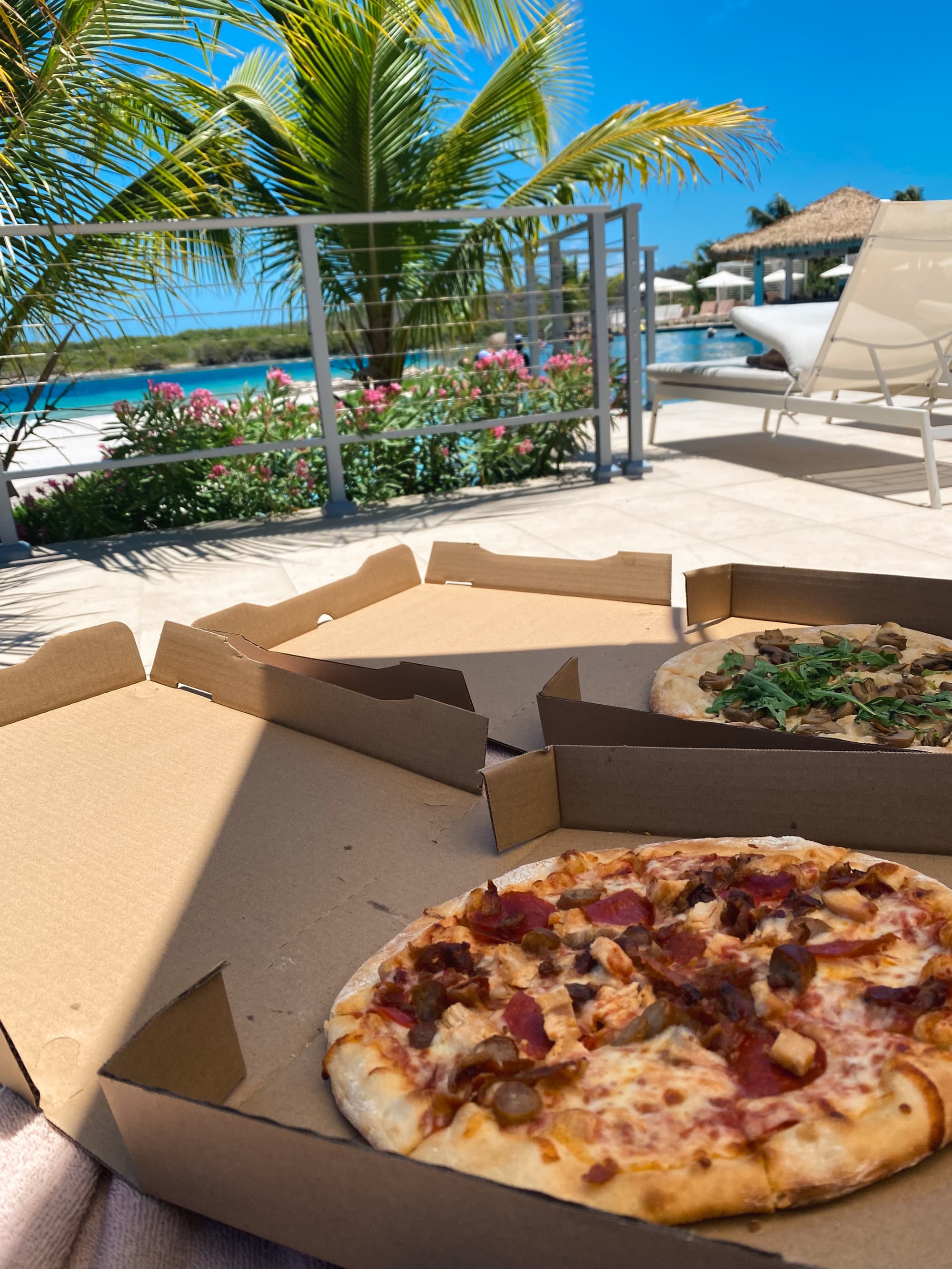 Two boxes of pizza at the poolside.