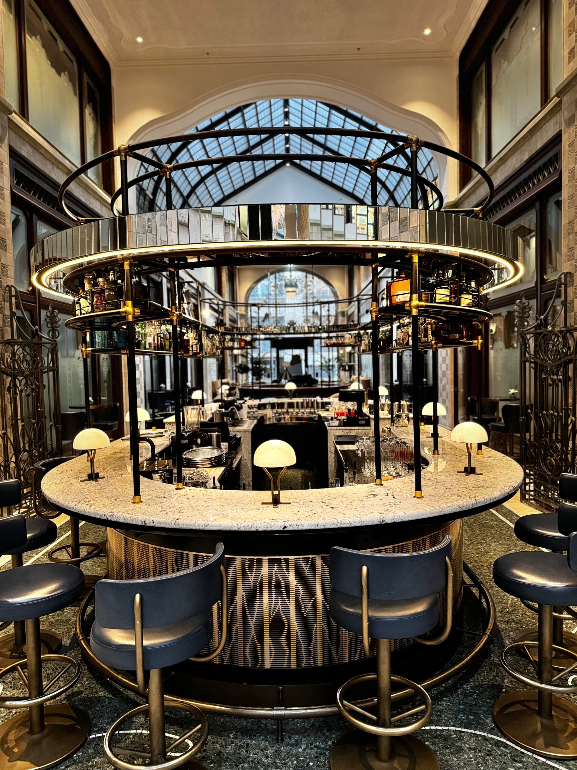 Upscale bar with blue swivel chairs and glass ceiling.