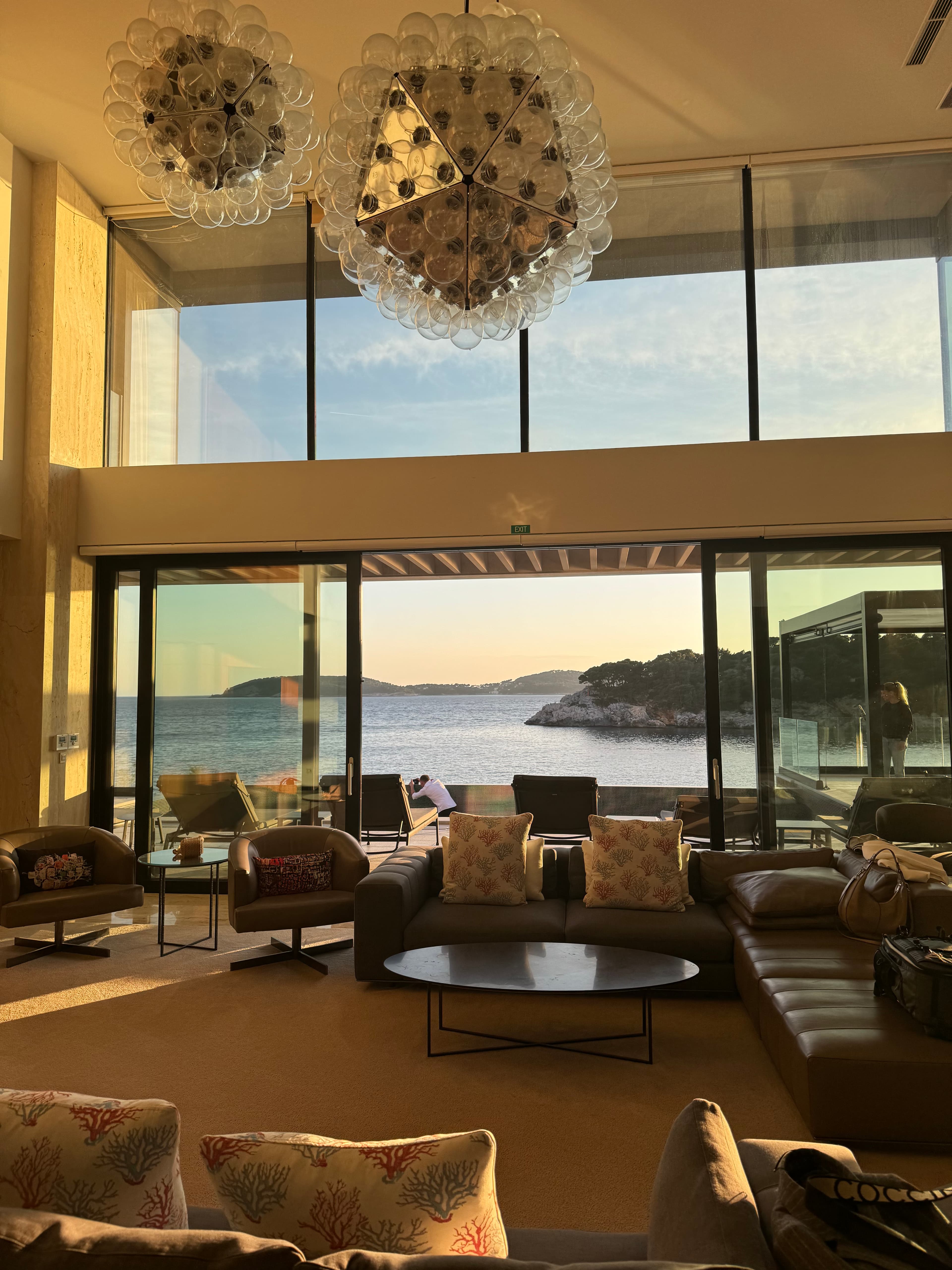 The interior of a beautiful villa with a plush lounge area and large windows looking out onto the ocean.