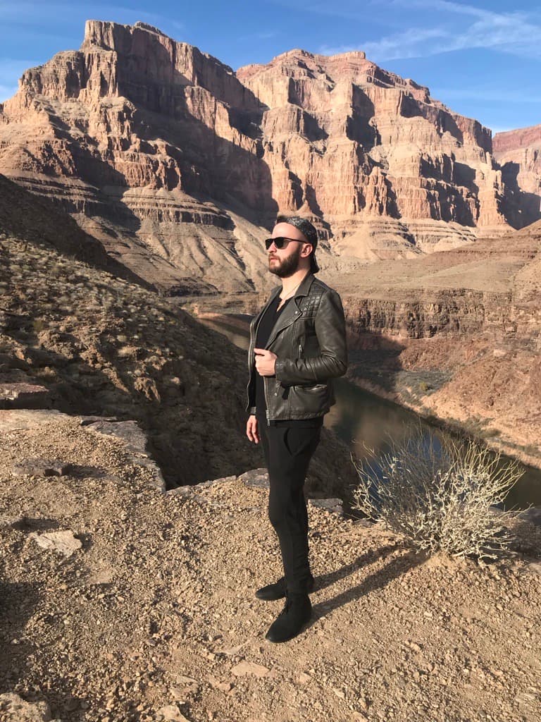 man with sunglasses standing in a picturesque canyon with blue sky