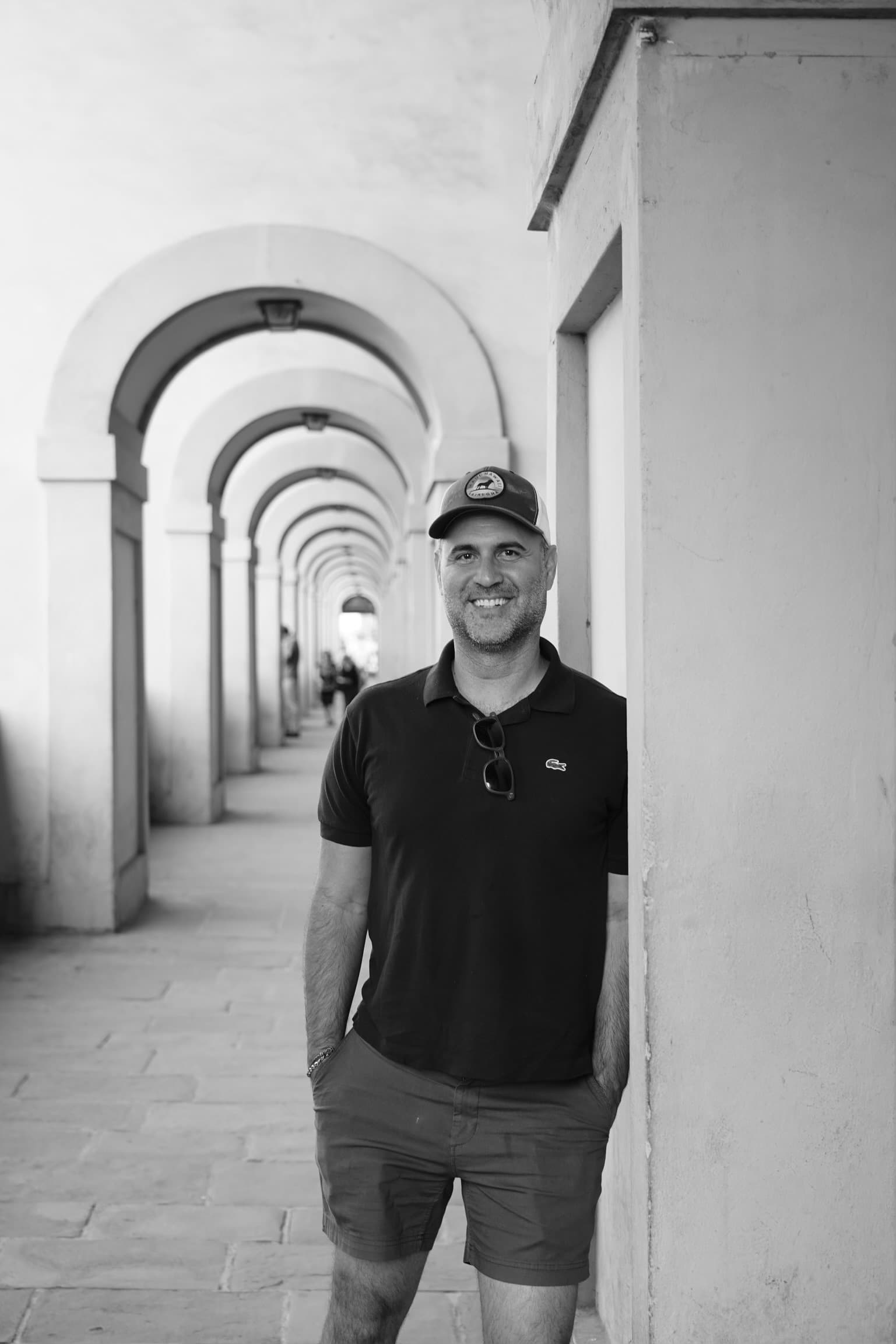black-and-white photo of a man leaning against a pillar in a colonnade
