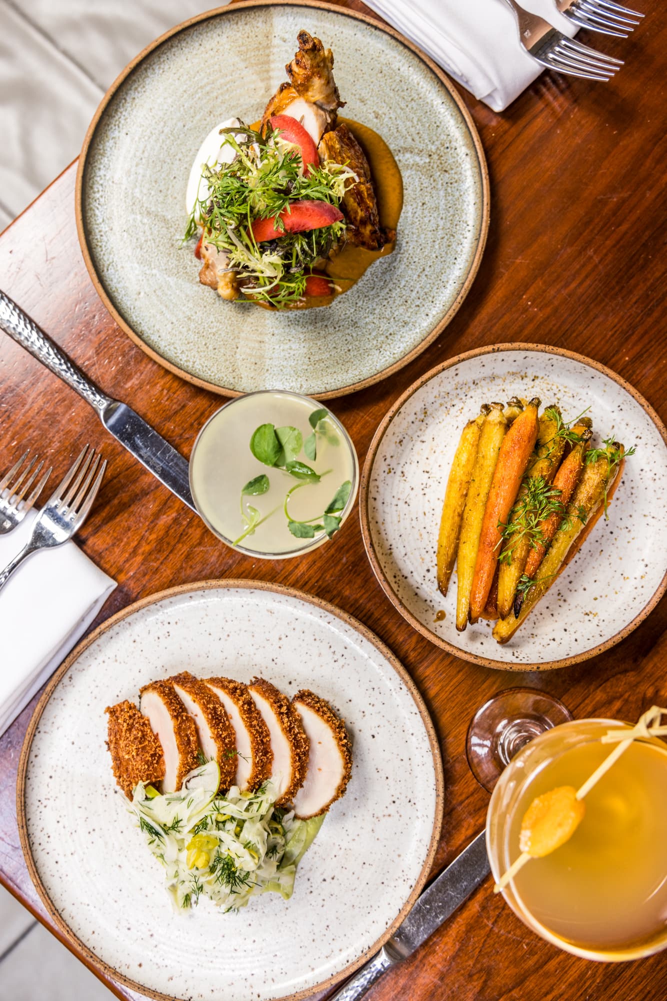 An above view of three plates of food sitting on a wooden table