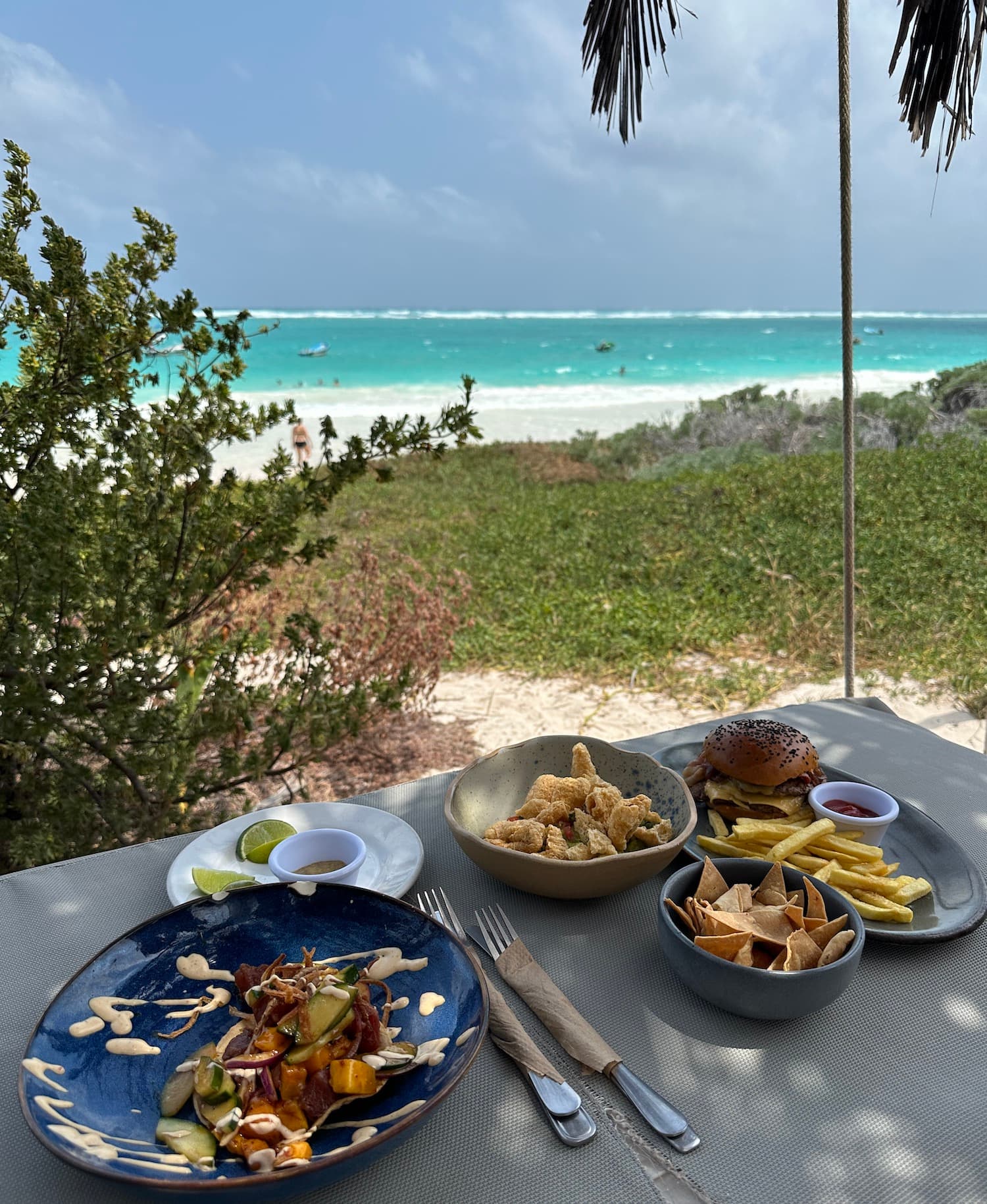 PLates of food on an outside table looking out onto the beach during the daytime