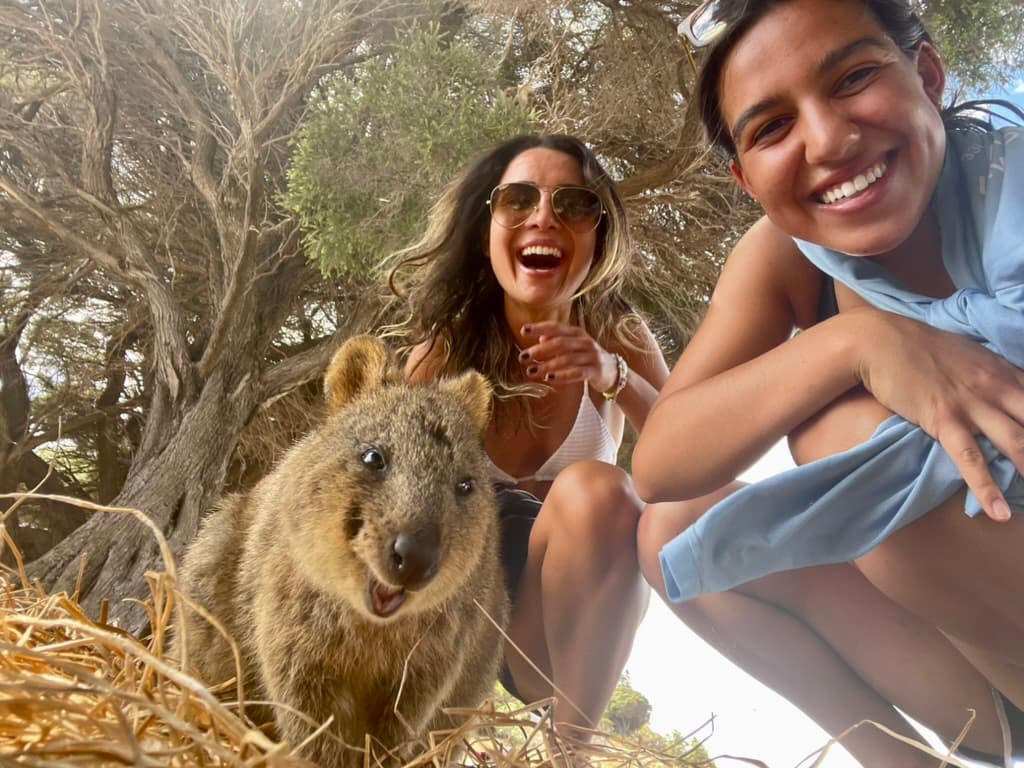 Two people posing with a kangaroo in the wild