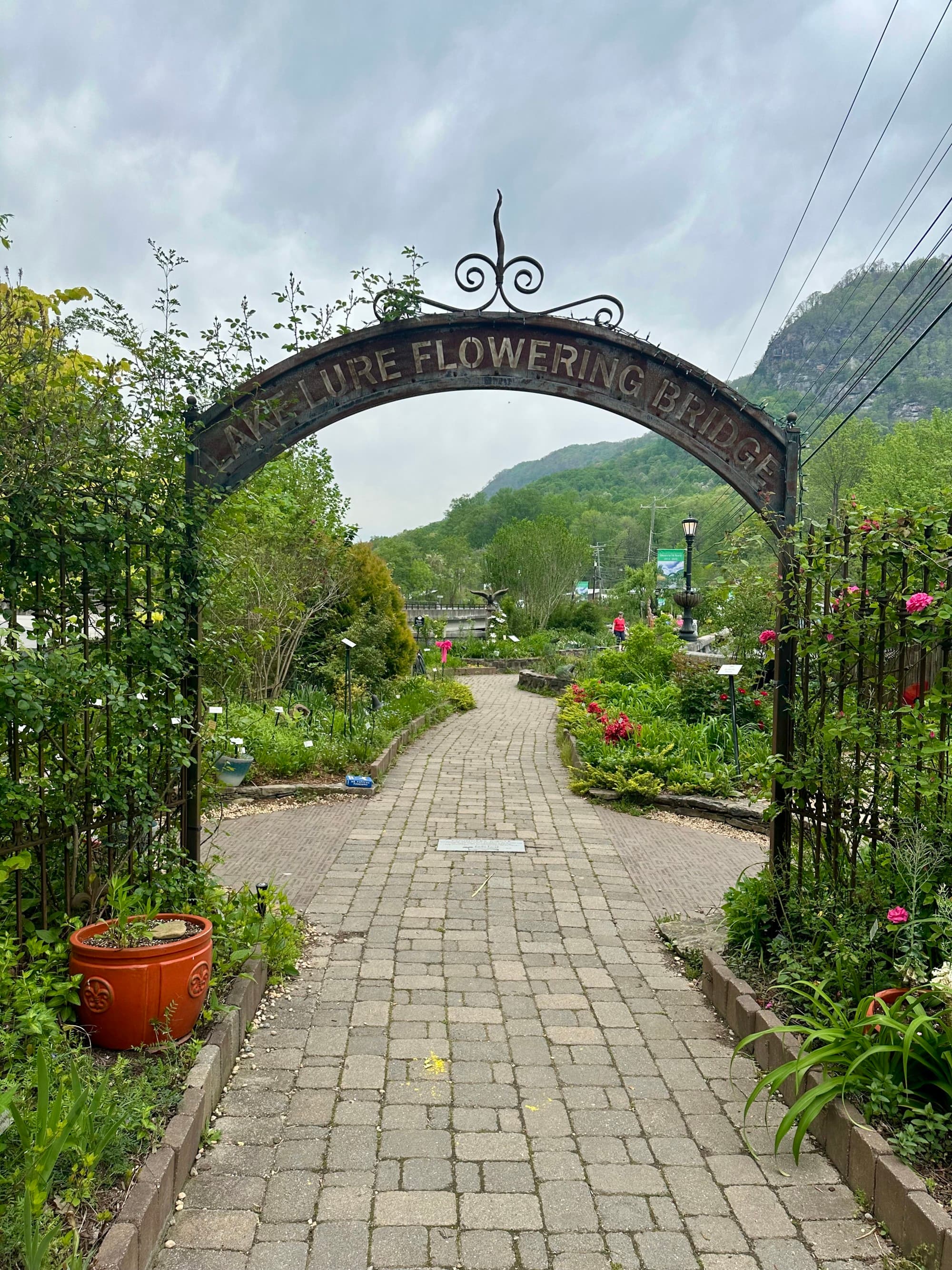 The entrance sign / archway to Lake Lure Flowering Bridge, surrounded by natural greenery and flowers.
