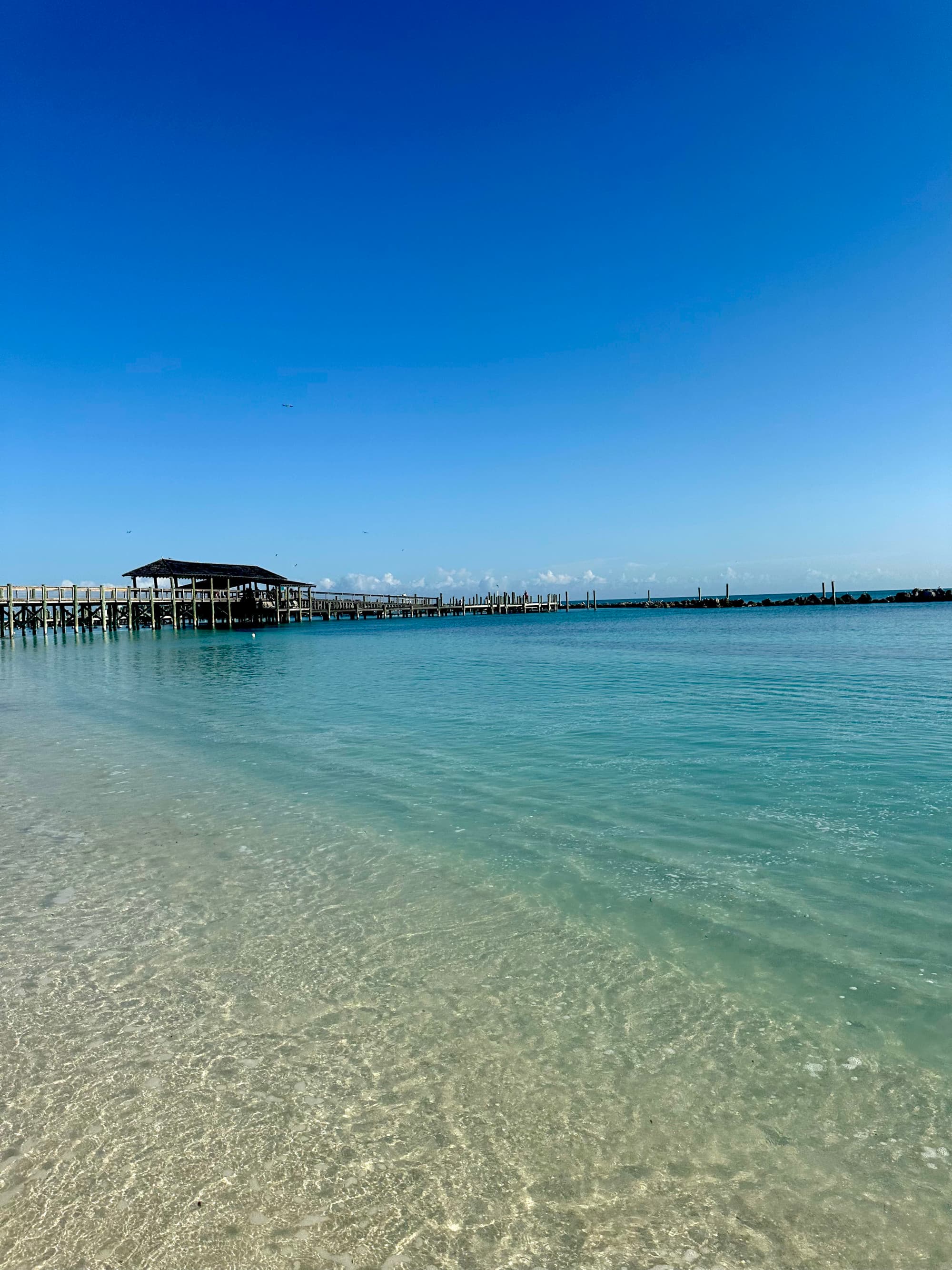A view of the Caribbean Sea with a lengthy pier extending out into the azure water.