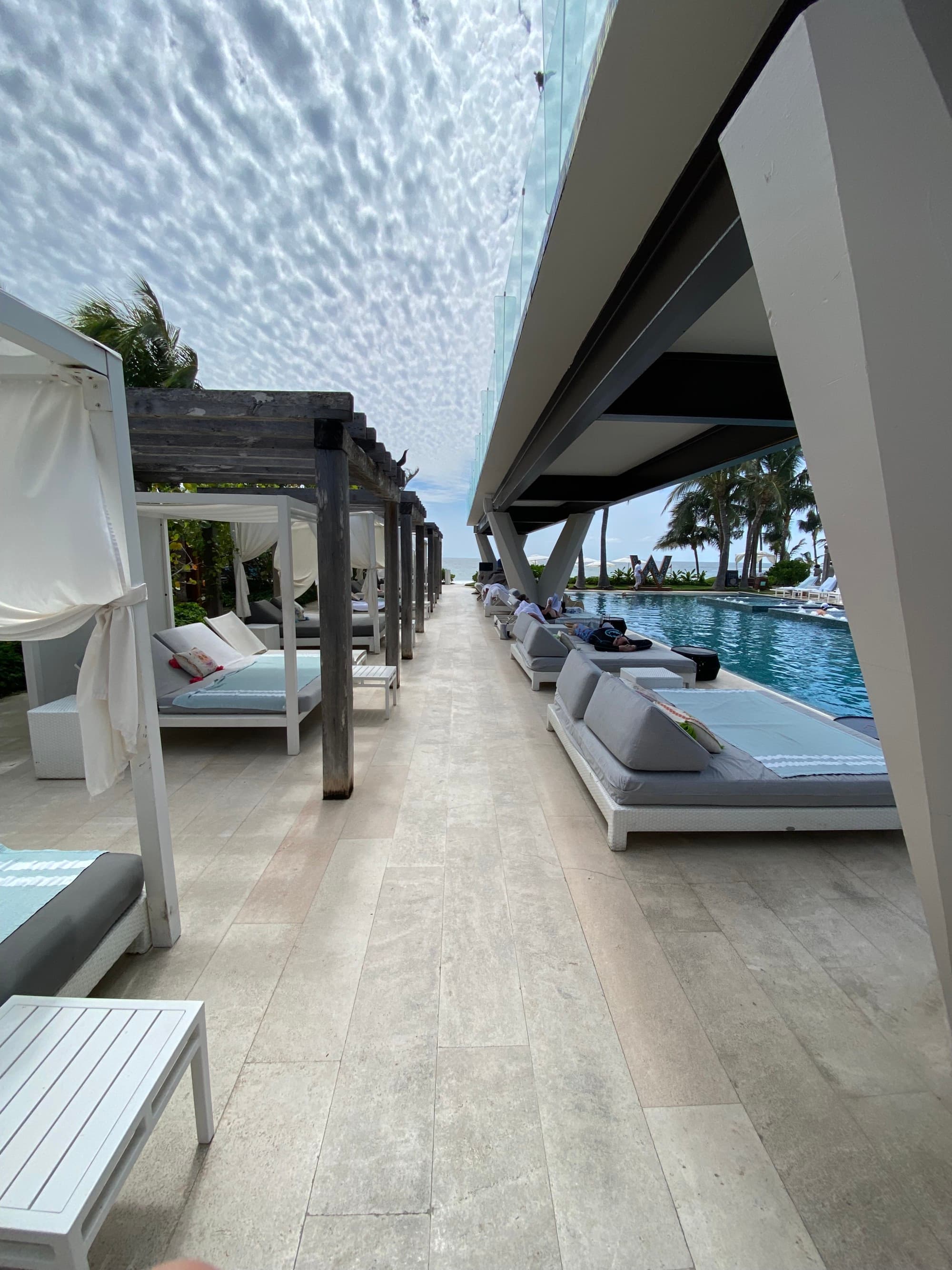 A pool area with lots of sun loungers during the daytime