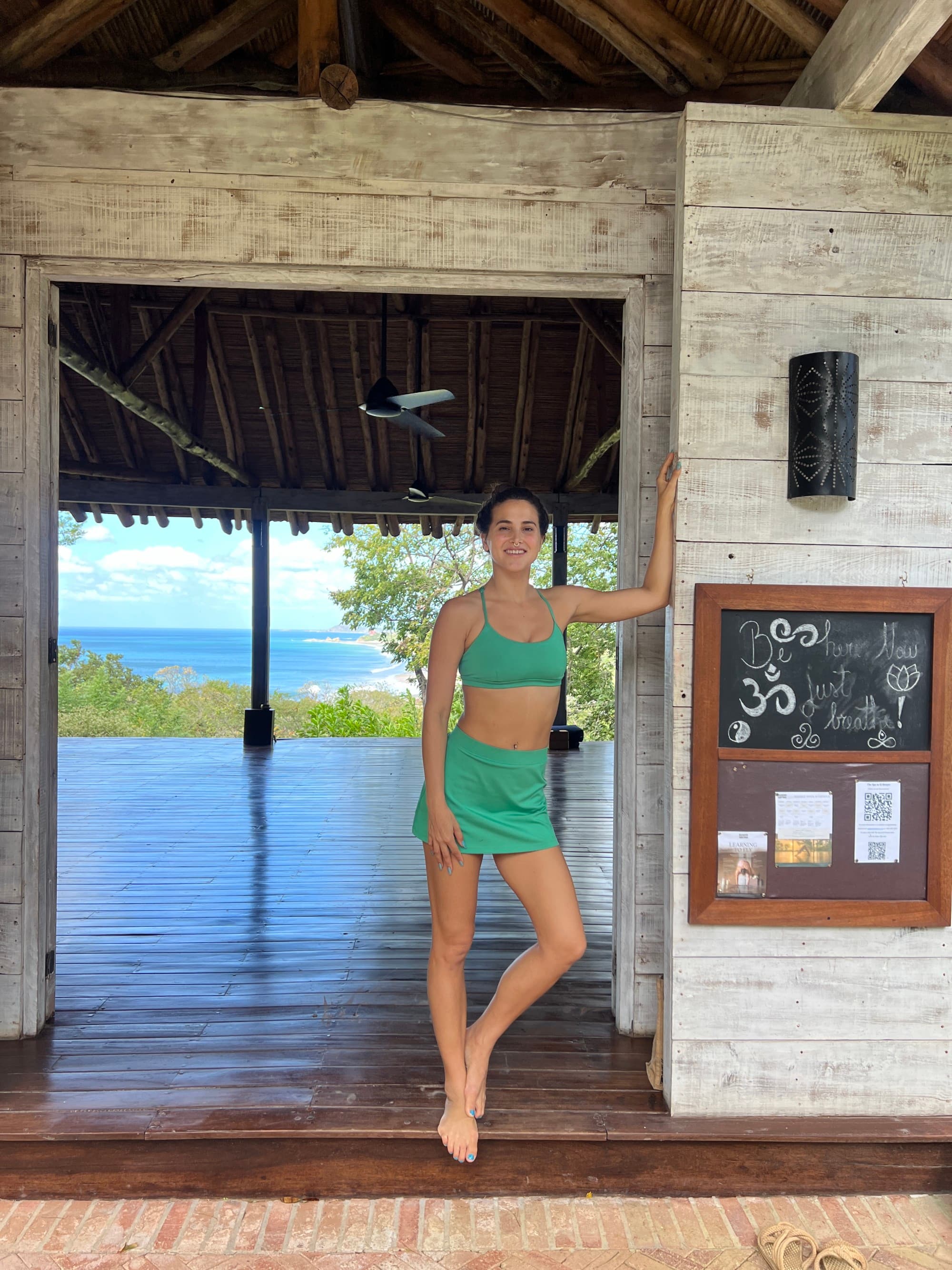 Travel advisor Emily standing in the doorway of an open area with a straw roof overlooking the beach