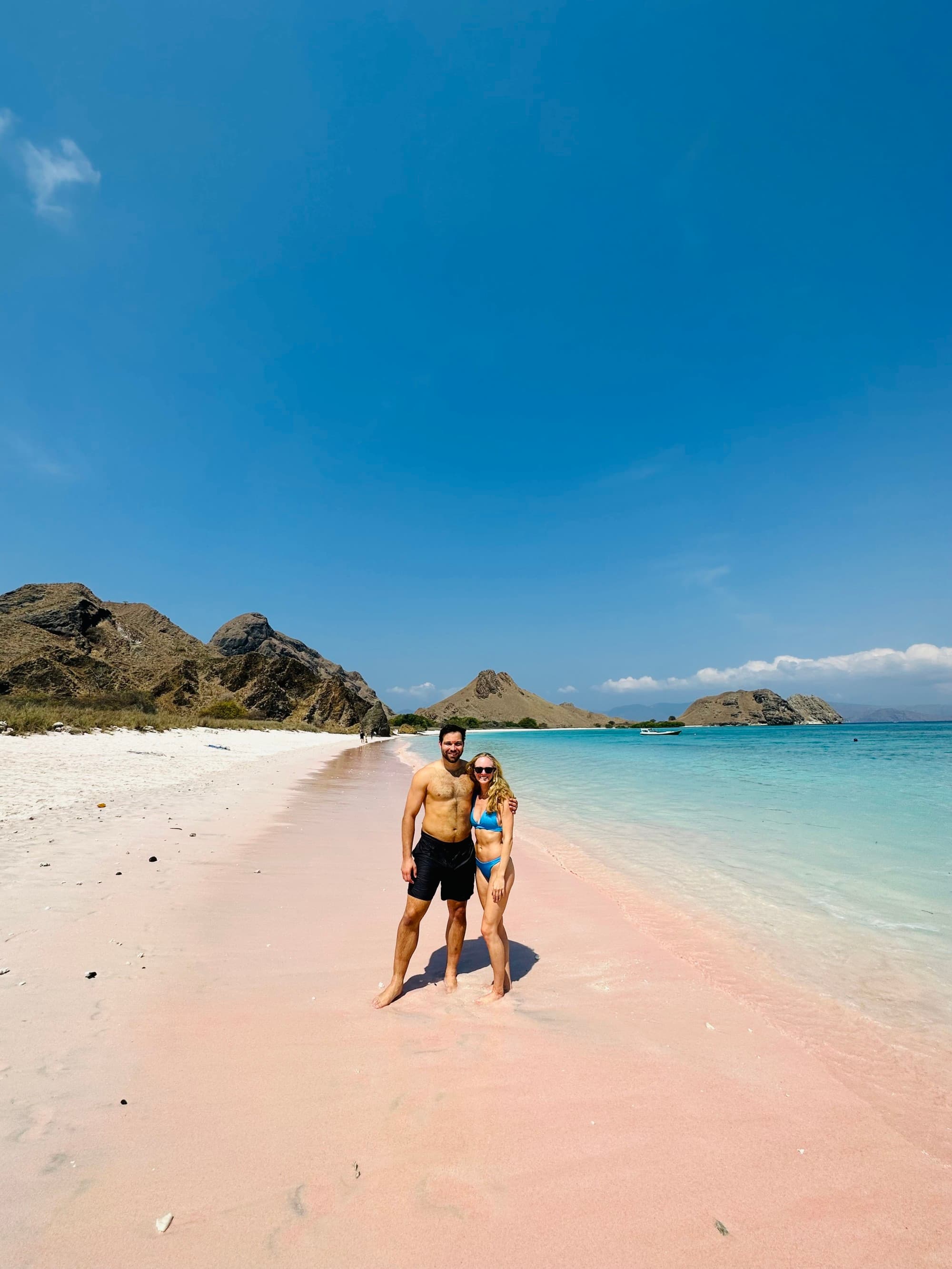 A couple posing on a beach by the water during the daytime
