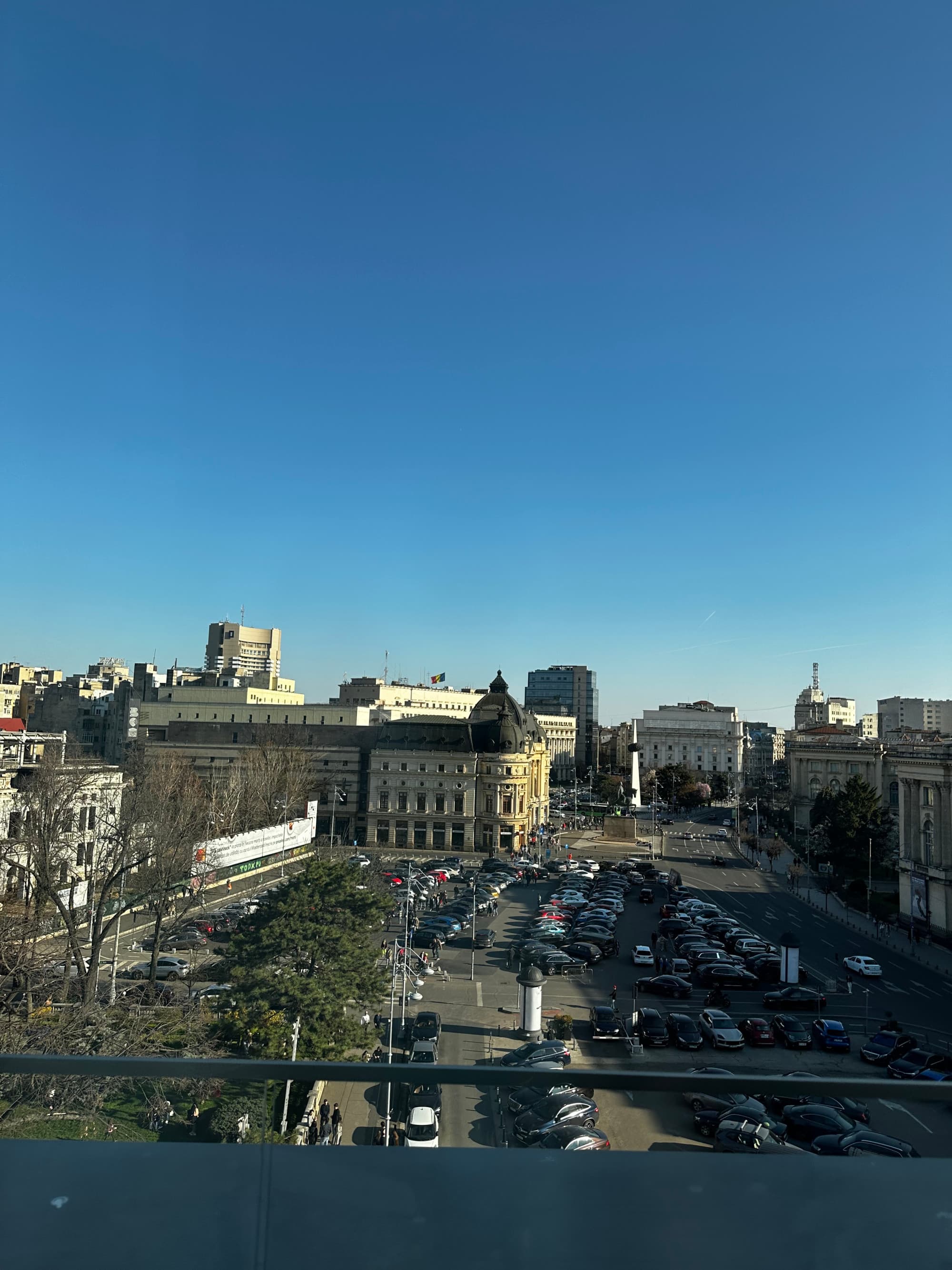 A view of a parking lot, buildings and trees from a hotel suite.