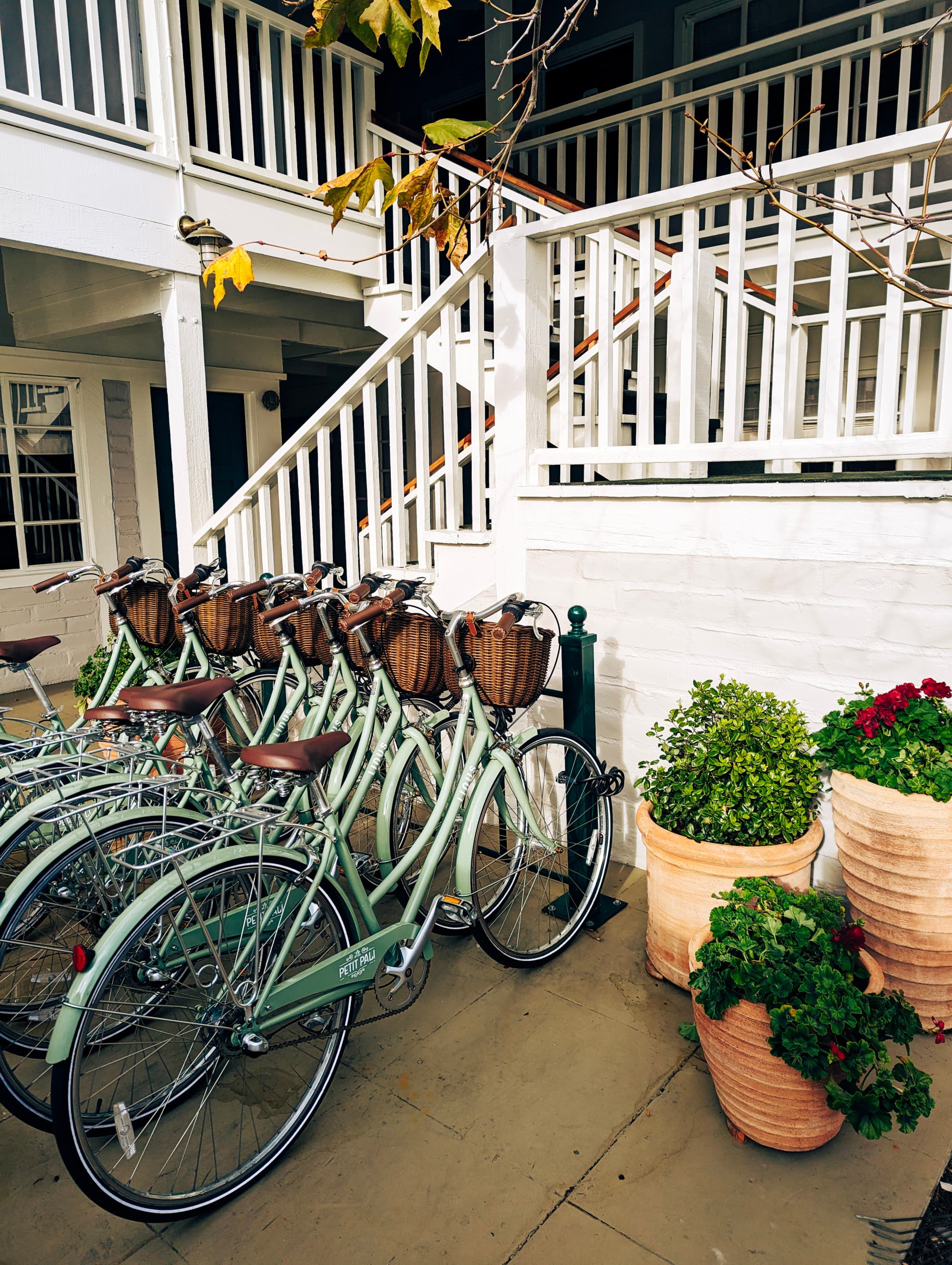 A bike rack full of teal green bikes next to a white railing staircase outside