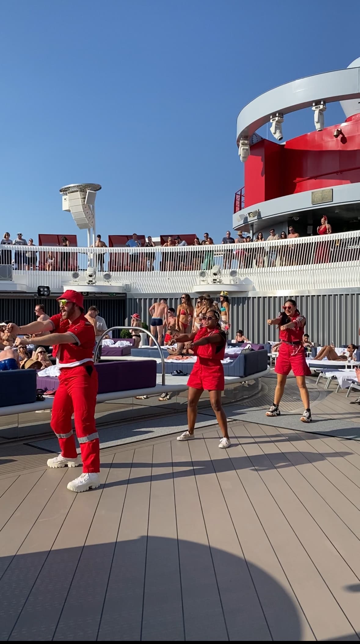 Dancers in red outfits performing on the deck by the pool area