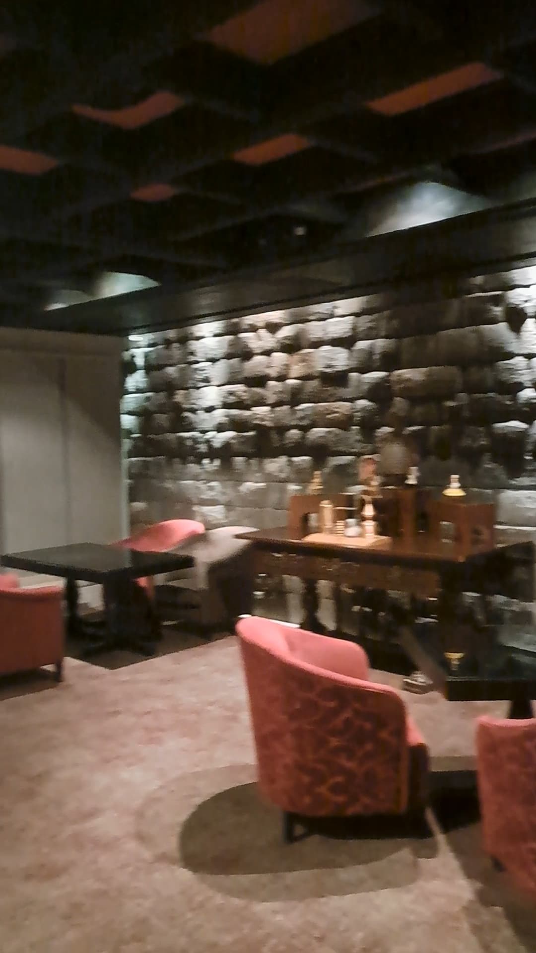 Bar area in hotel with red armchairs, low ceilings and gray stone walls