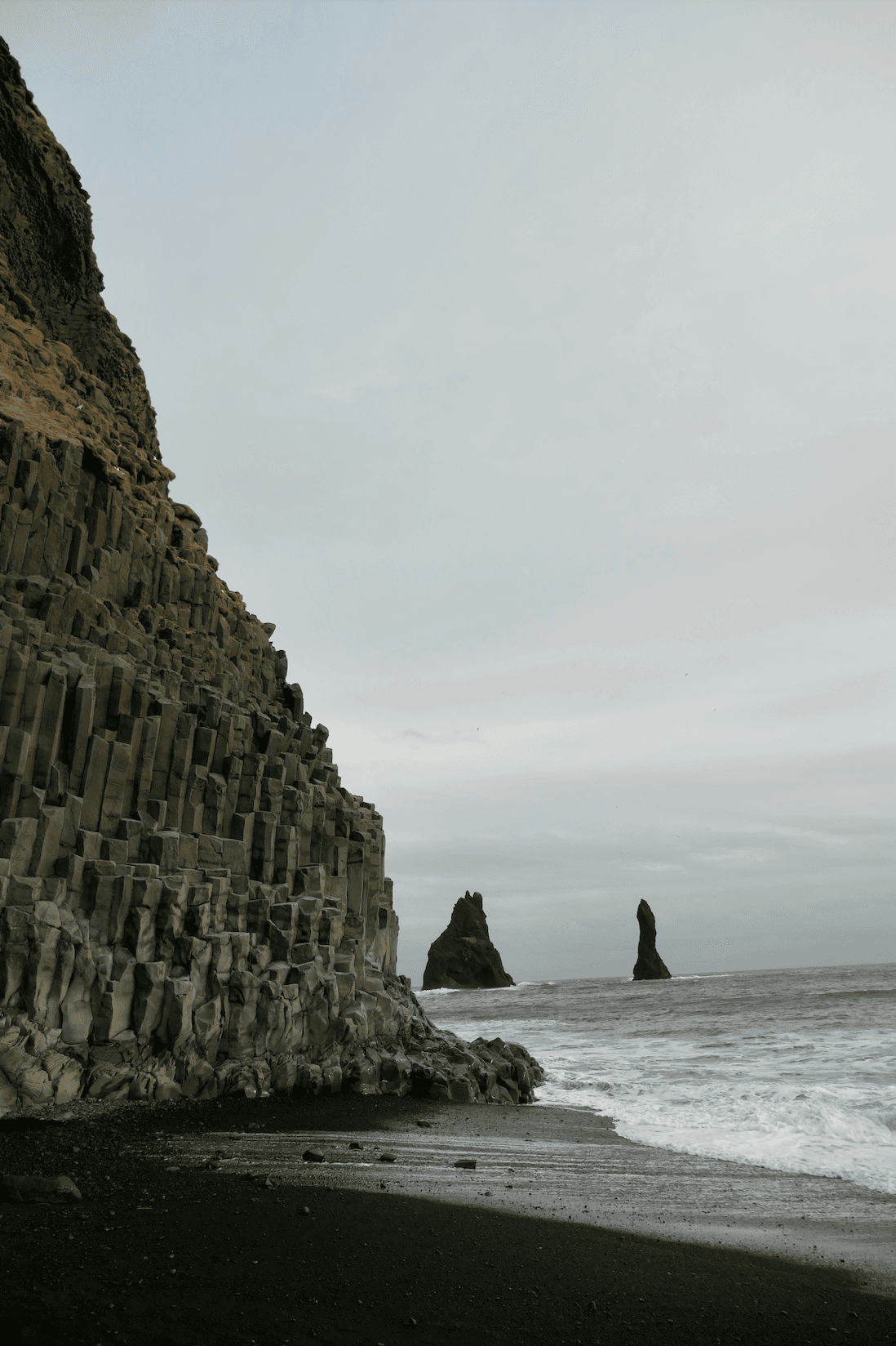 Reynisfjara Beach with a large suspended mountain scape that ends on the ocean shoreline - Kati Vervack