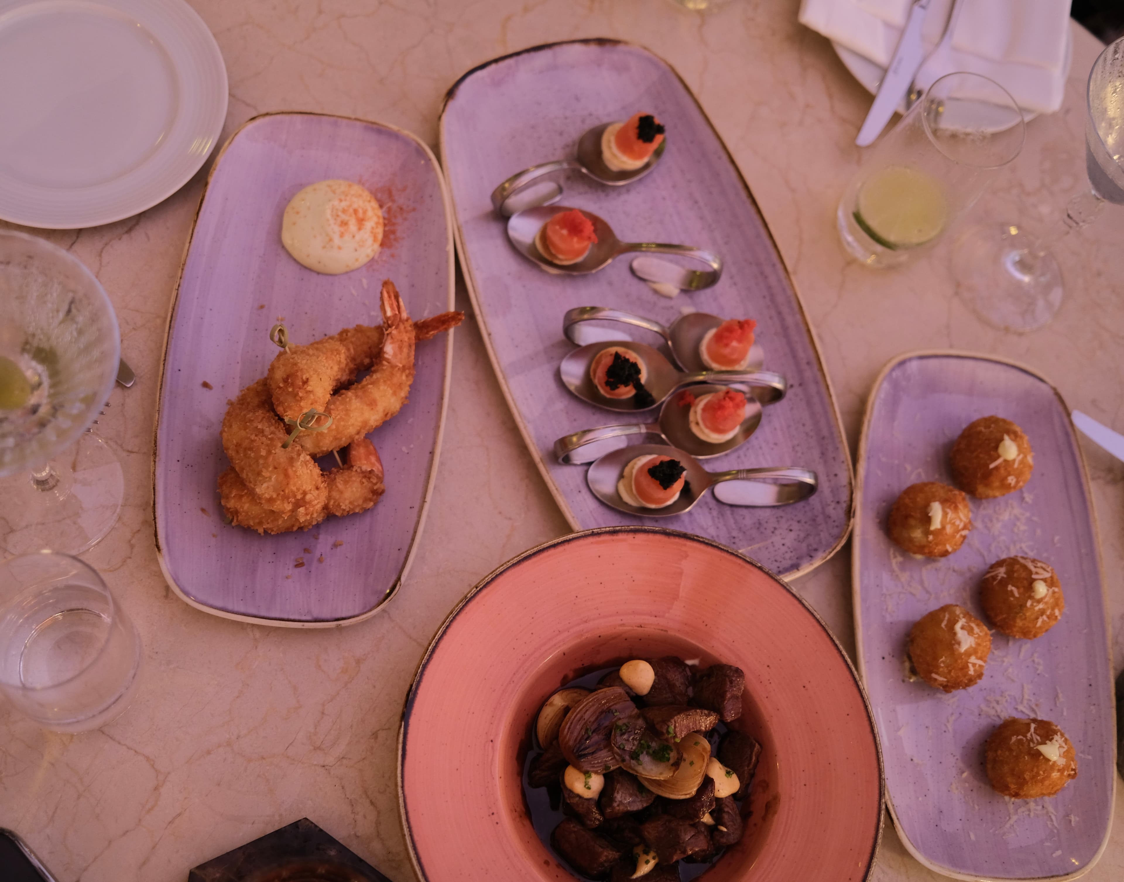 A table with purple and pink plates and small bites on top of them.