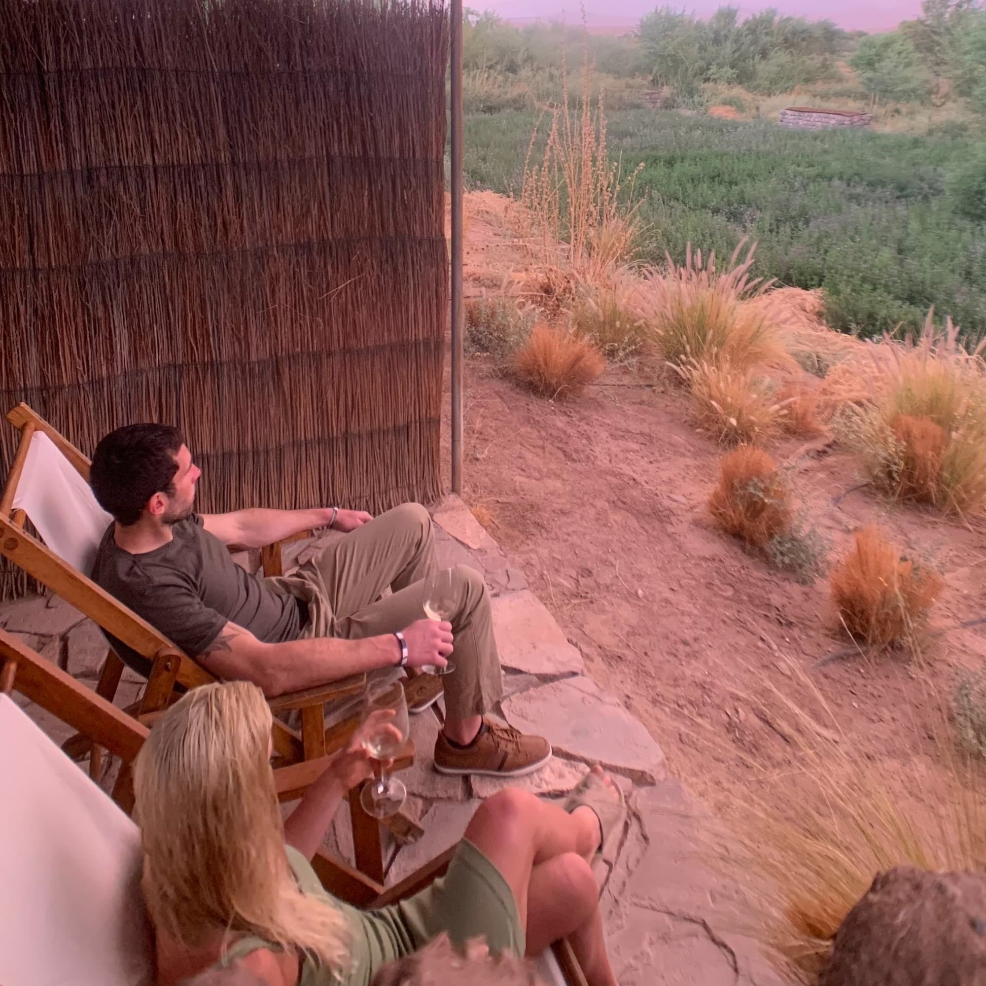 a woman and a man sit on chairs under a tent overlooking the desert