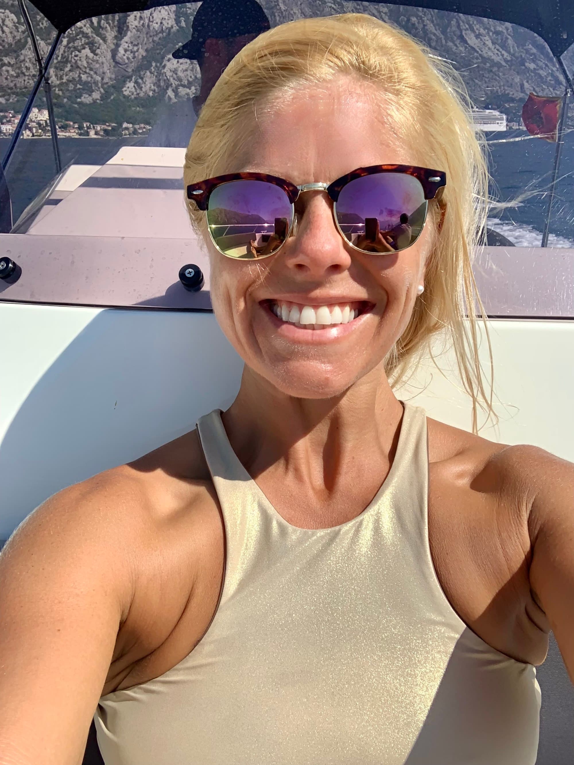 a woman in a gold halter top and sunglasses smiles