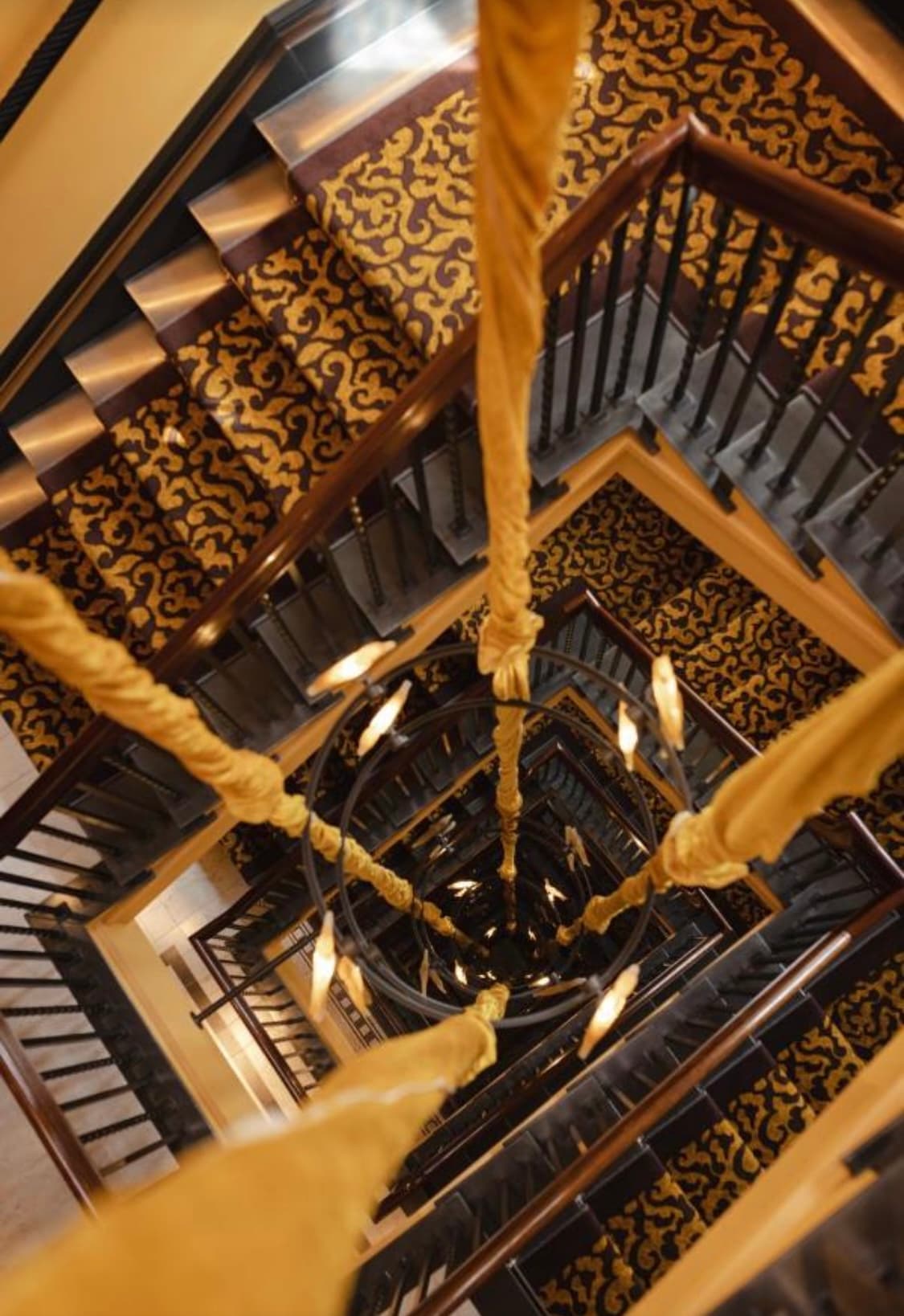 Hotel staircase that winds down multiple levels with classy carpeting.
