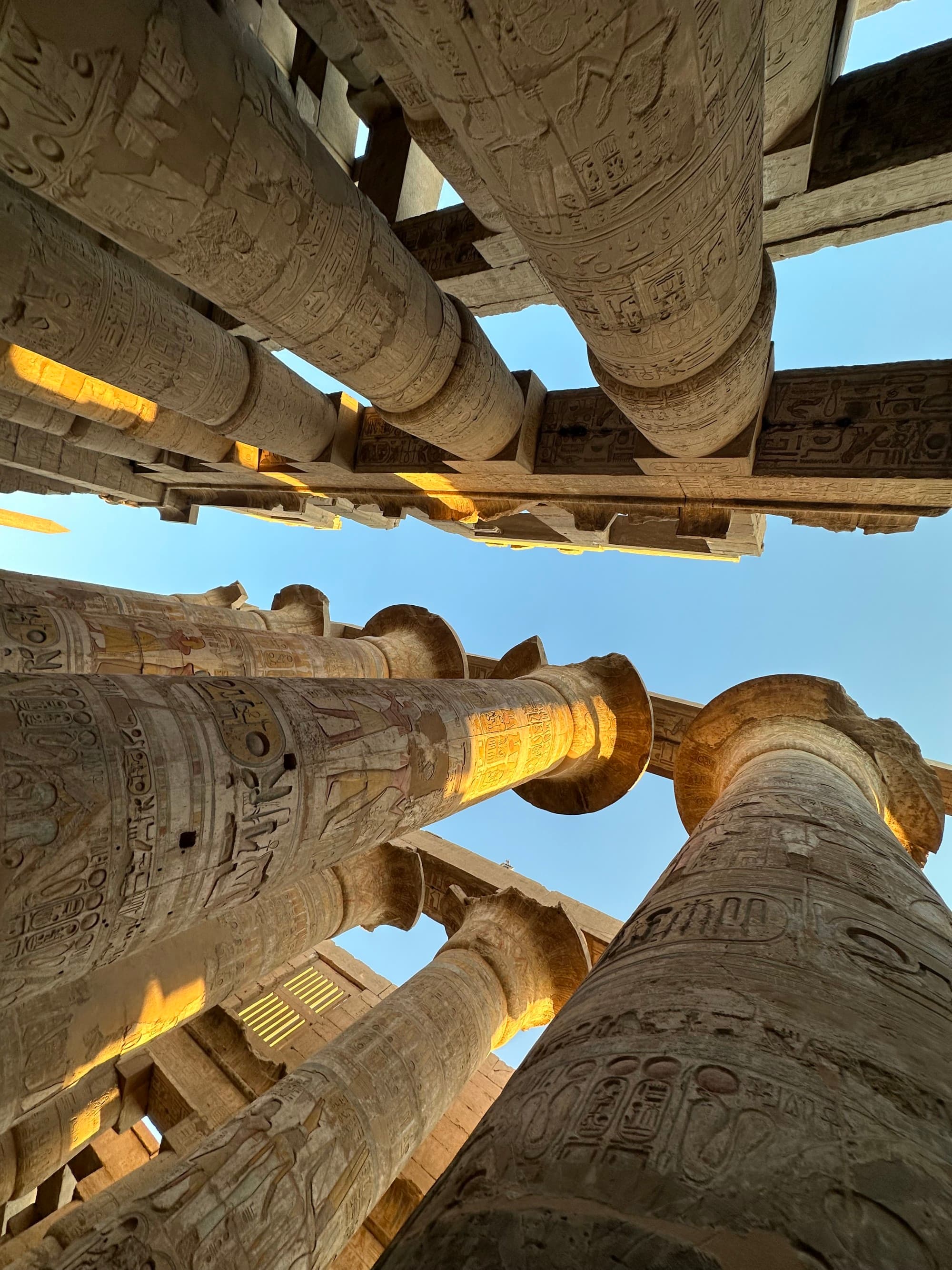 A view towards the sky of pillars with intricate carvings at Karnak Temple
