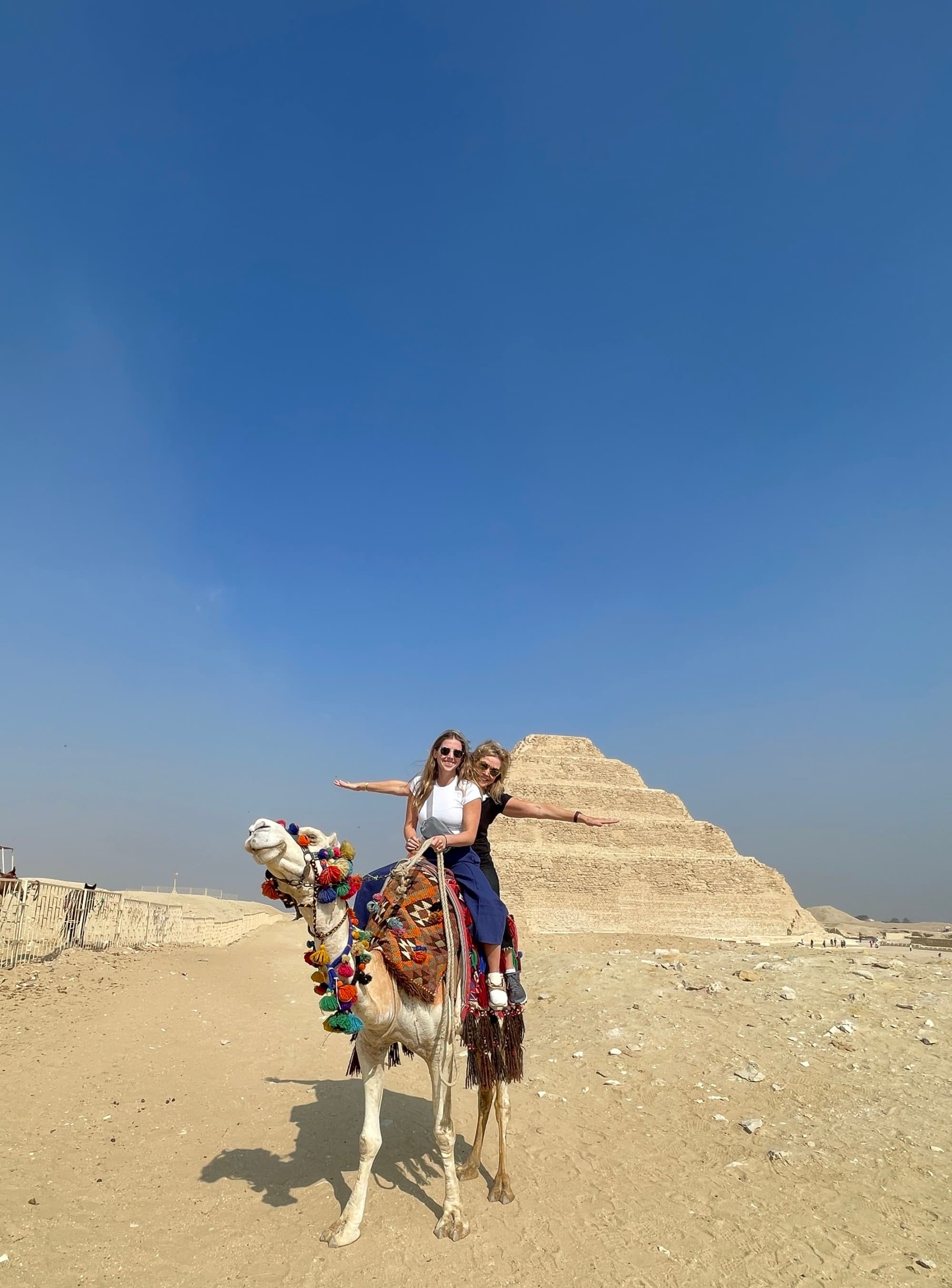 Eliza and another traveler on a camel in front of Saqqara Pyramid
