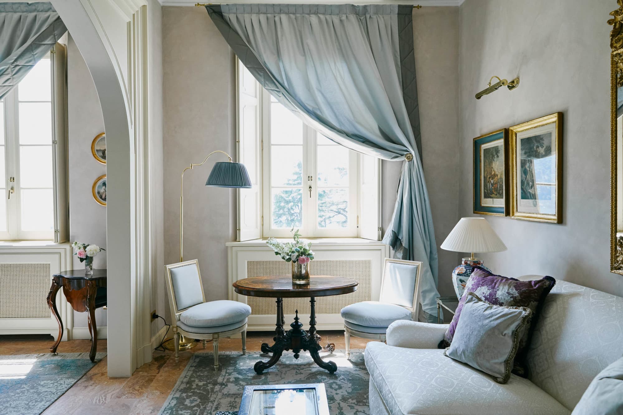 two blue chairs sit in front of a window partially covered by a blue curtain