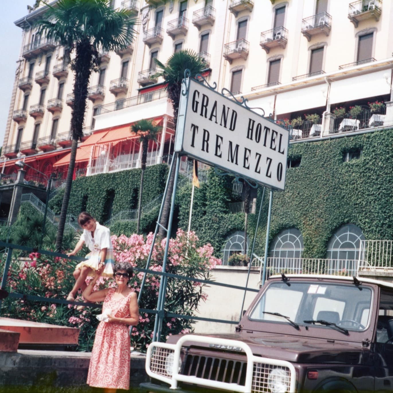 two woman near a car in front of a grand hotel