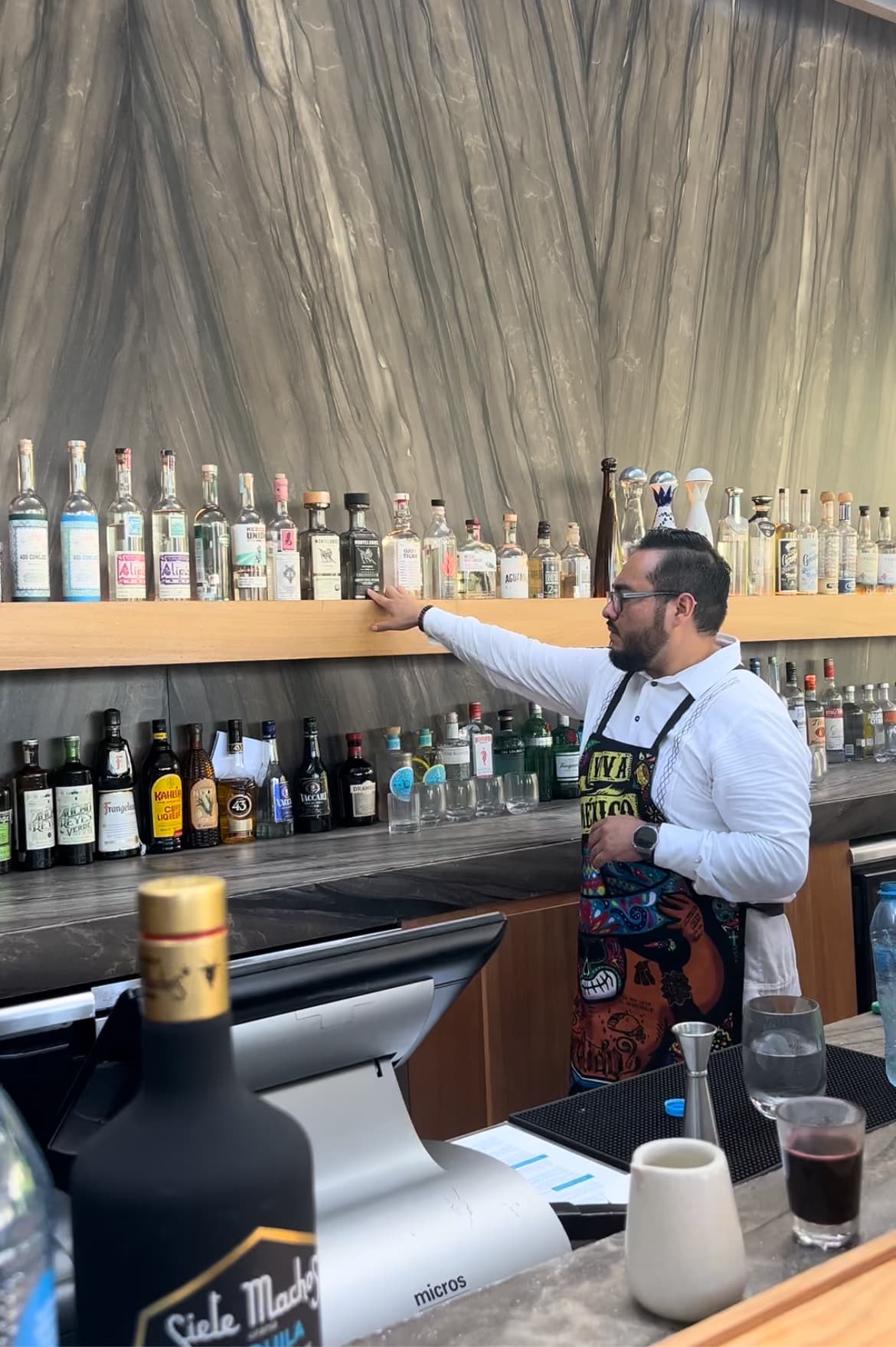 A bartender highlighting all of the margarita ingredients behind the bar.