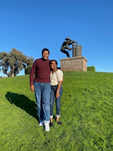 a woman and a man embrace each other on a grassy hill