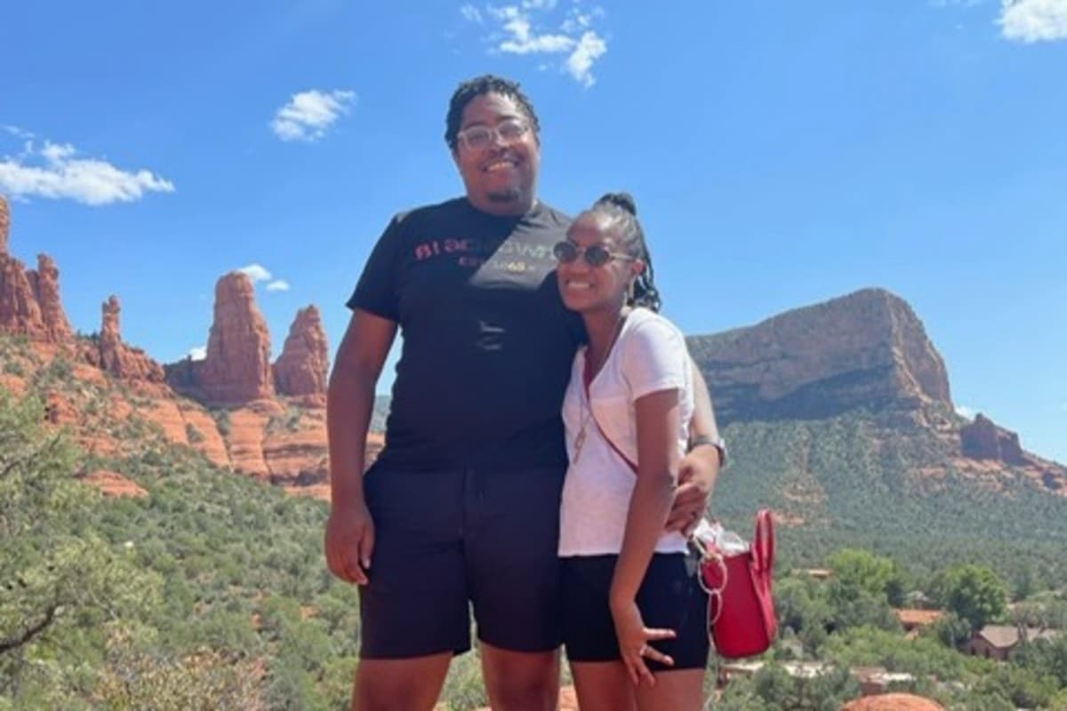 a woman and a man stand next to each other on a hike in a red-rock desert