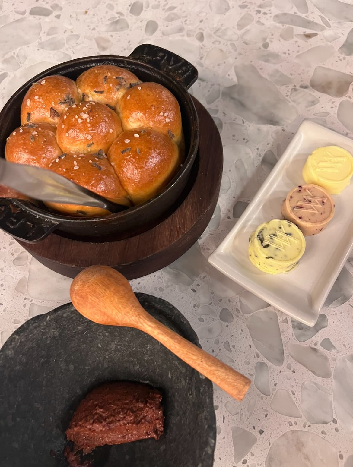 Bread and butter on fancy plates over a stone table.