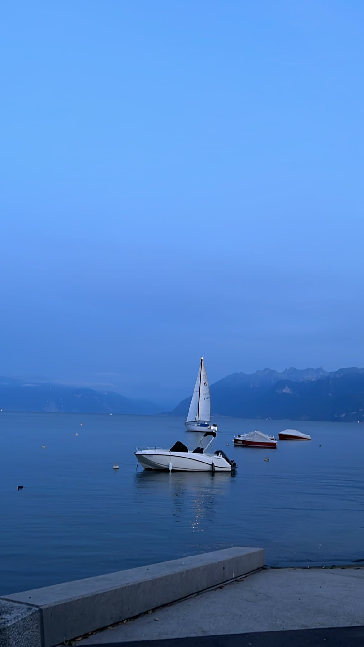 Ships in the sea with a deep blue hue in the sky that matches the ocean.