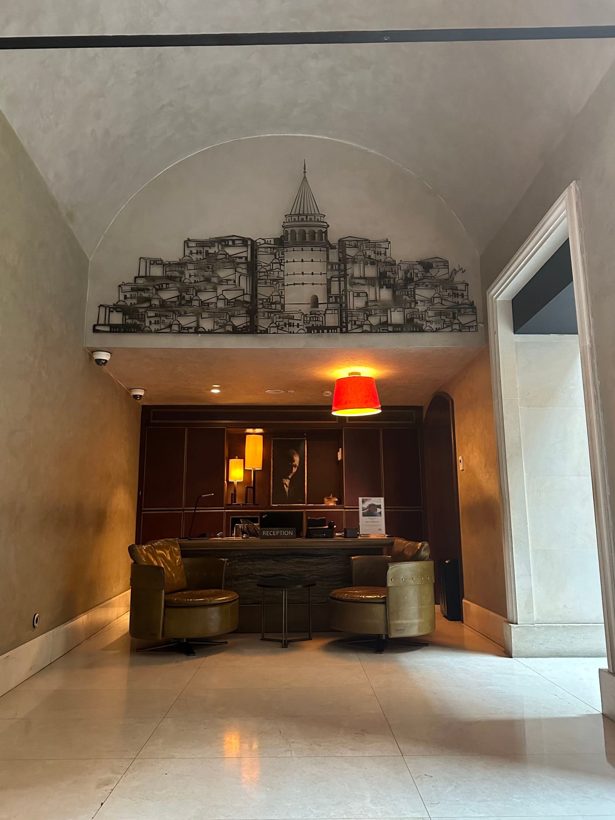 A tile entryway with a wooden desk in an alcove with leather chairs in front and lamps surrounding