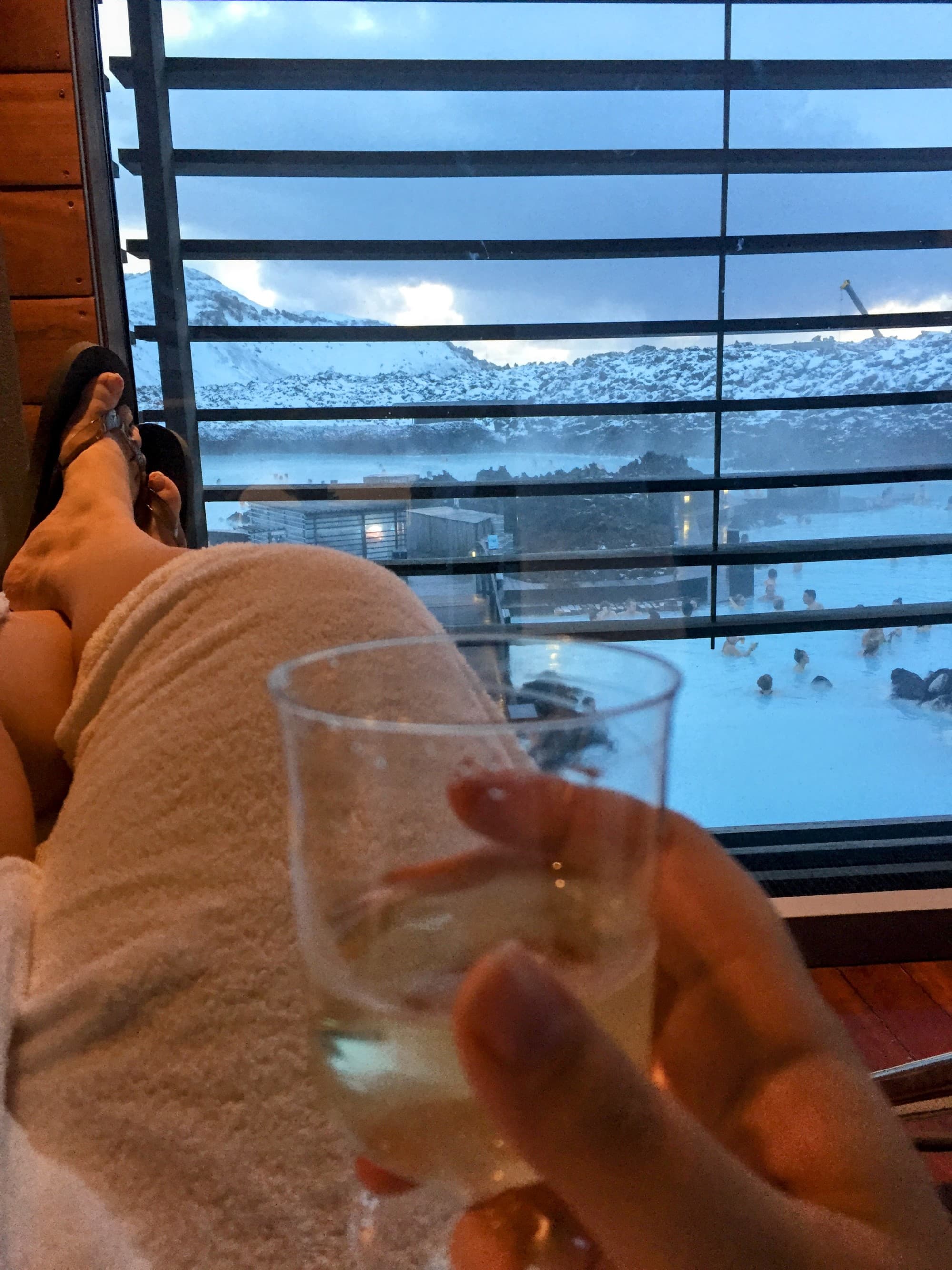 Laying near a window with a glass of champagne in hand and views of the snowy mountains outside.