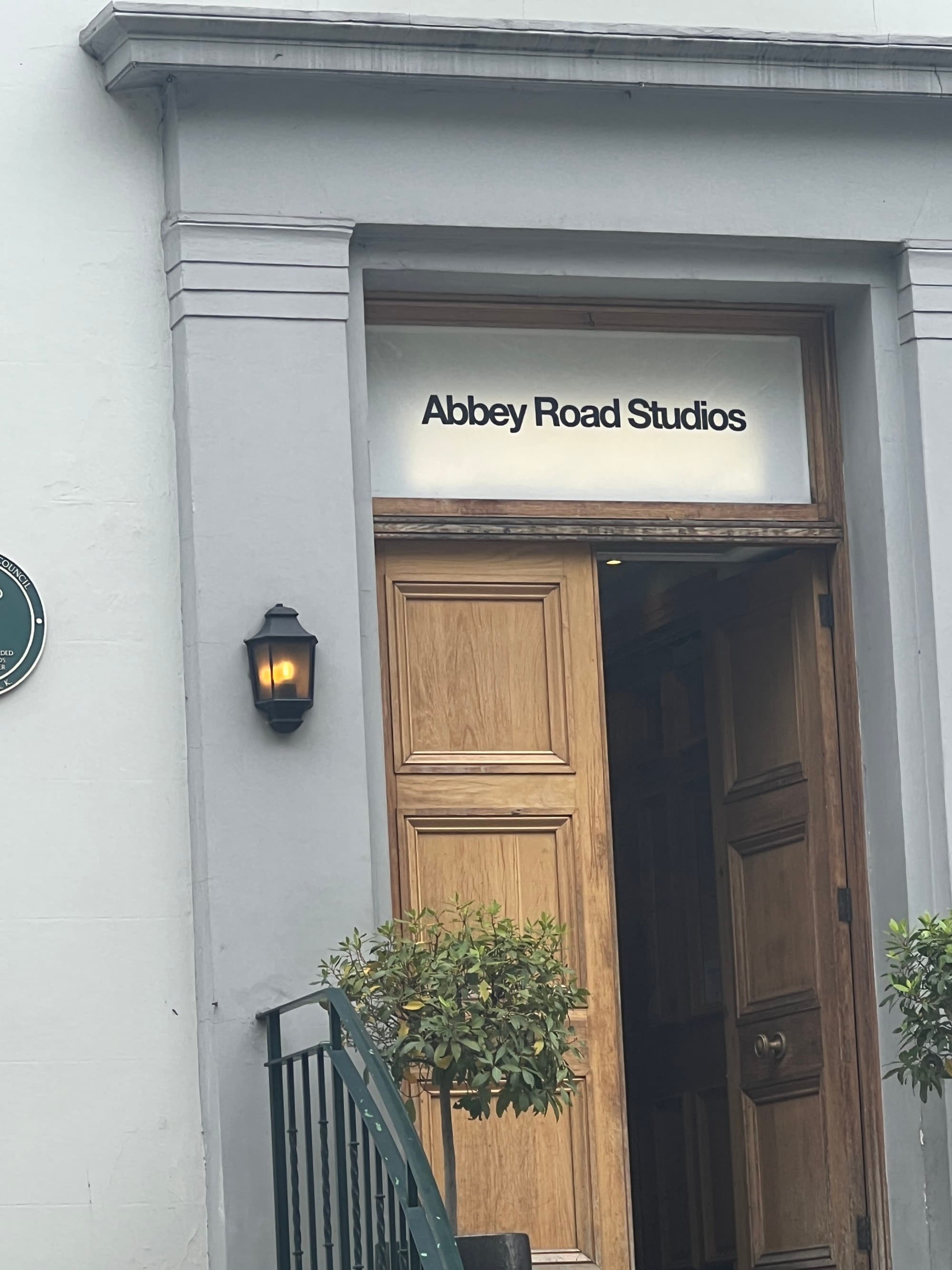 A white building with a sign reading "Abbey Road Studios" above a wooden door