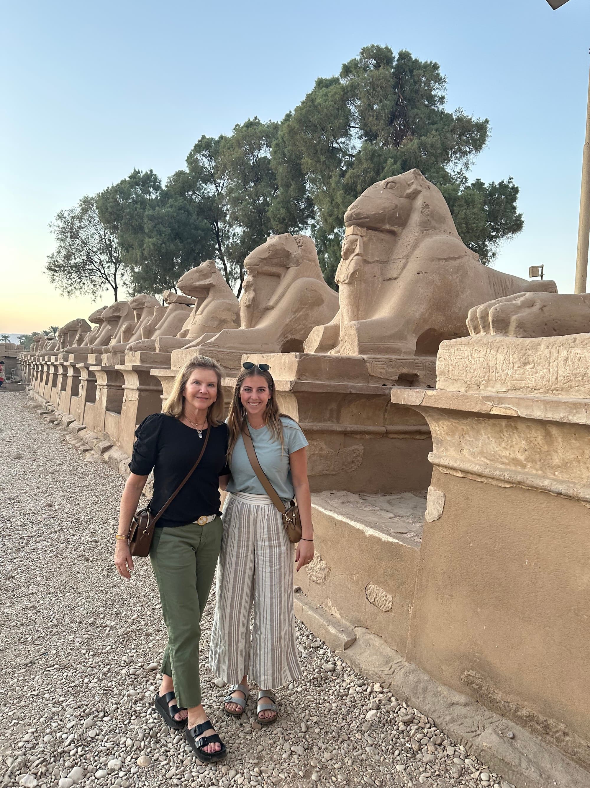 Travel Advisor Eliza in Birkenstocks and linen pants posing with another traveler next to stone carvings