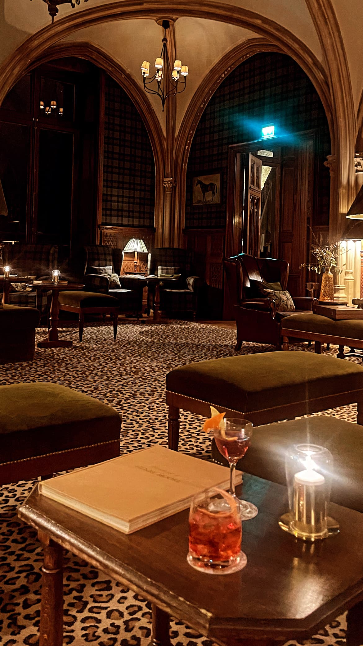 Various tables and benches on top of a leopard printed carpet beneath arched ceilings and grand chandeliers.
