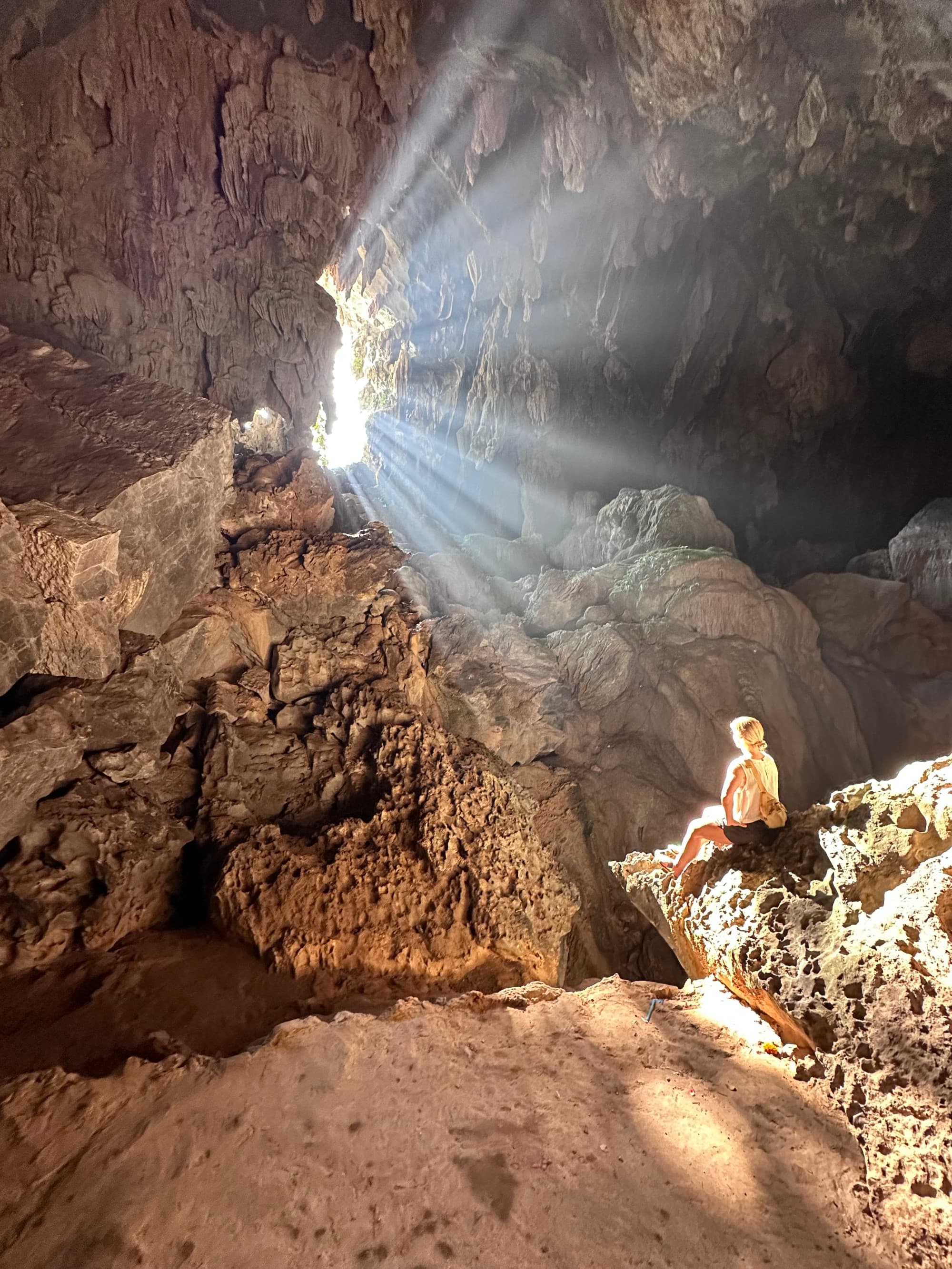 a woman sits in a sun-lit cave