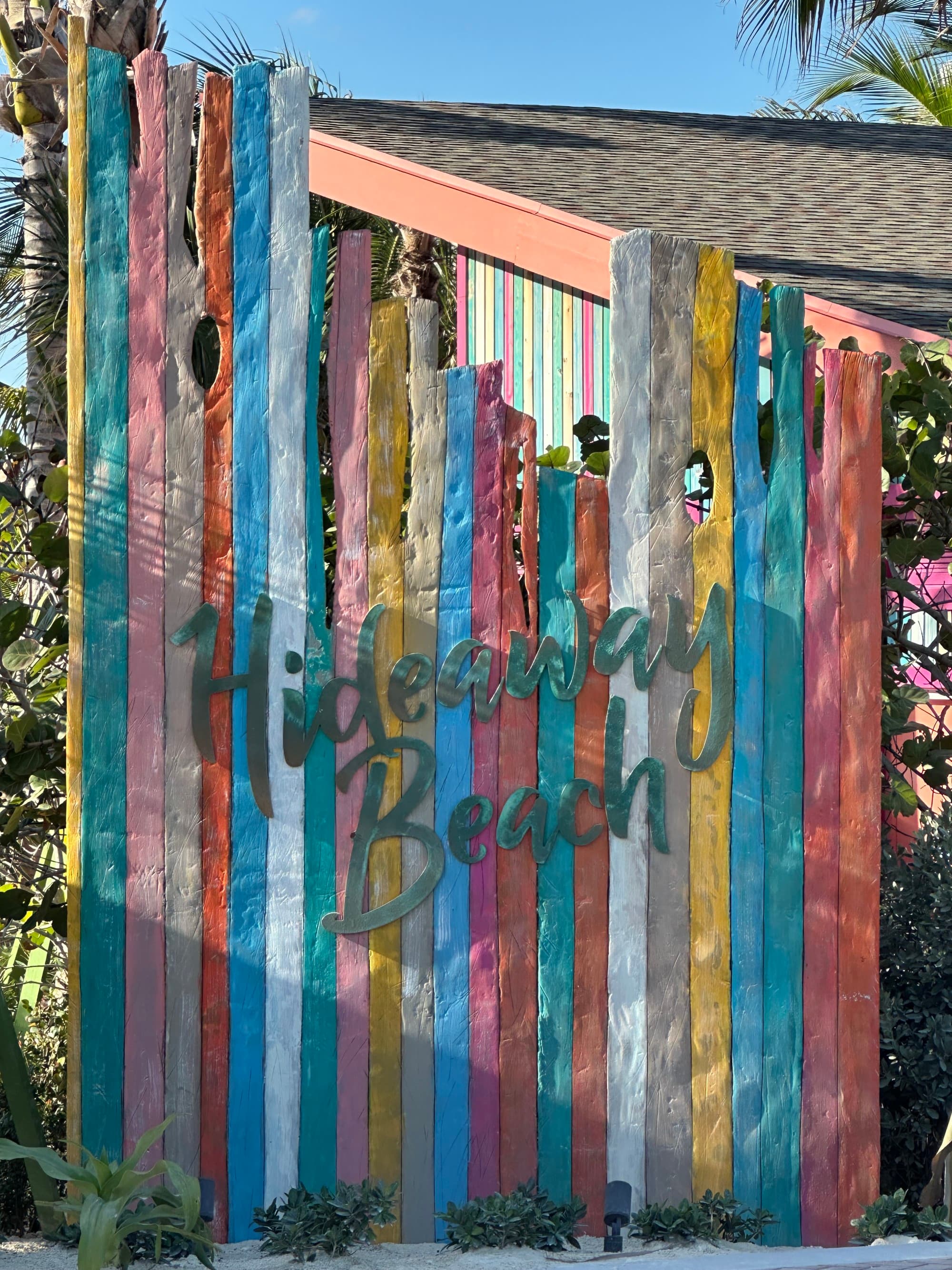A colorful driftwood sign that says Hideaway Beach.