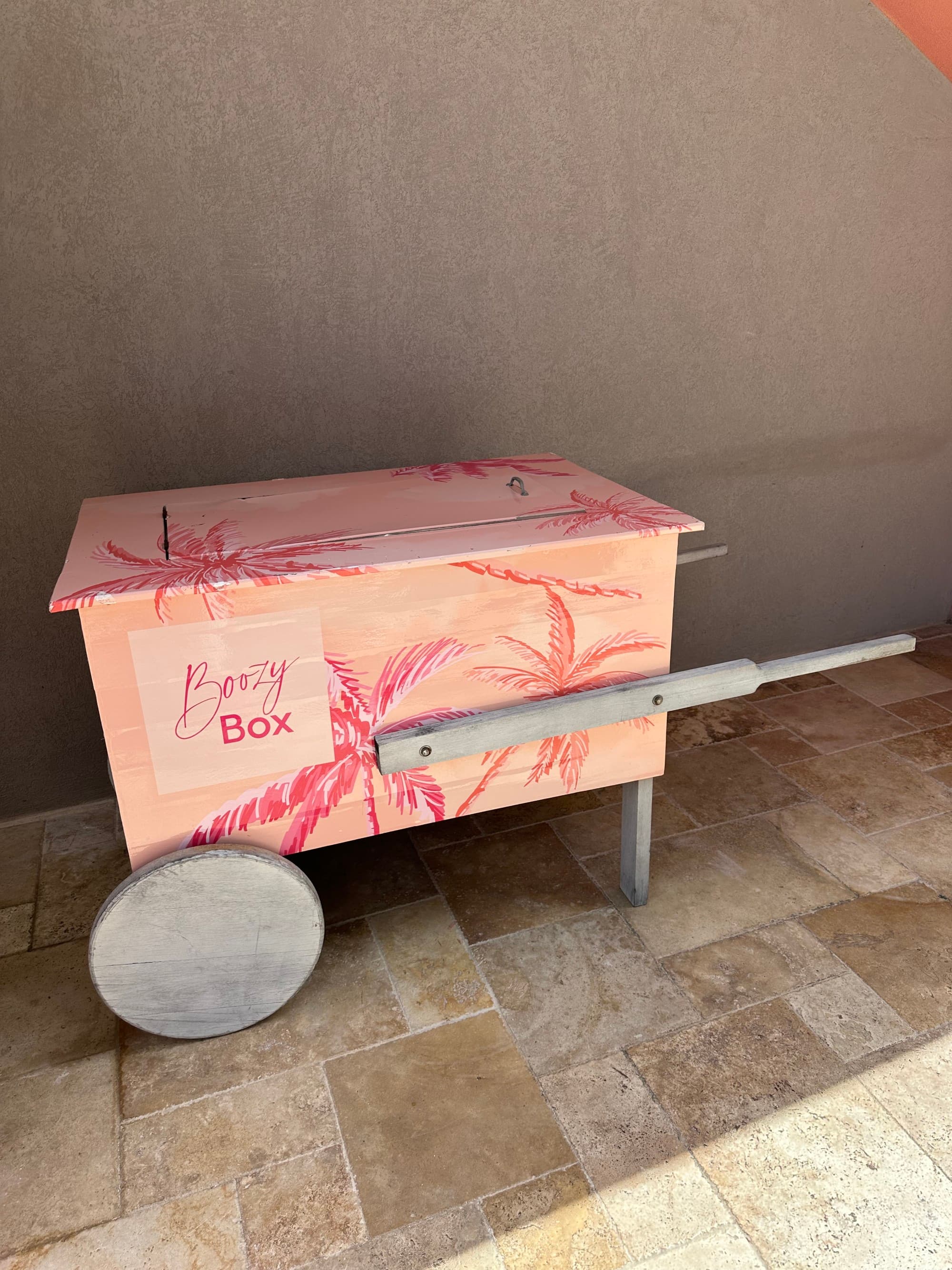 A picture of a pink food cart with pink palm tree artwork painted onto it.