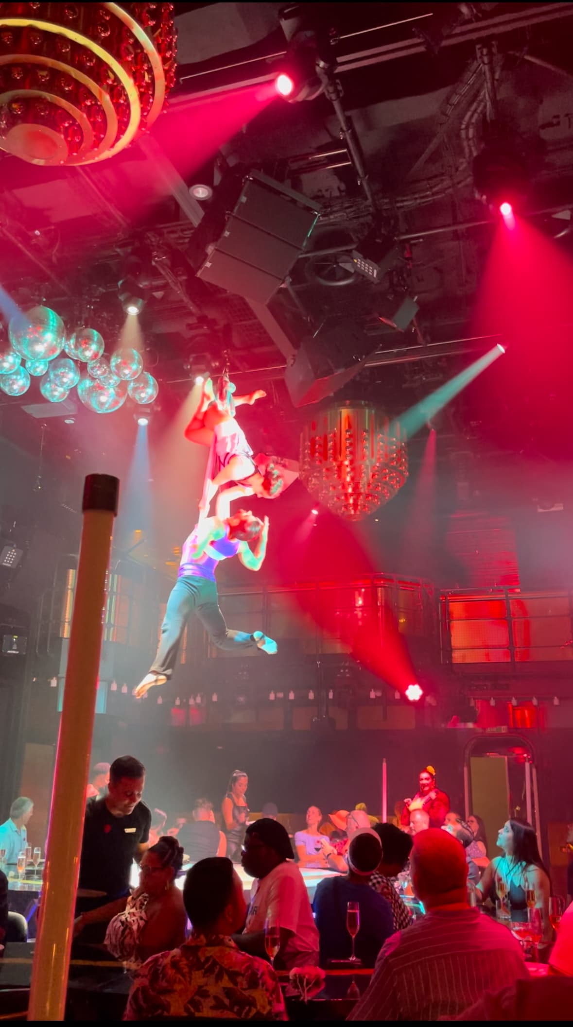 Aerialist performing above an audience with bright red lighting