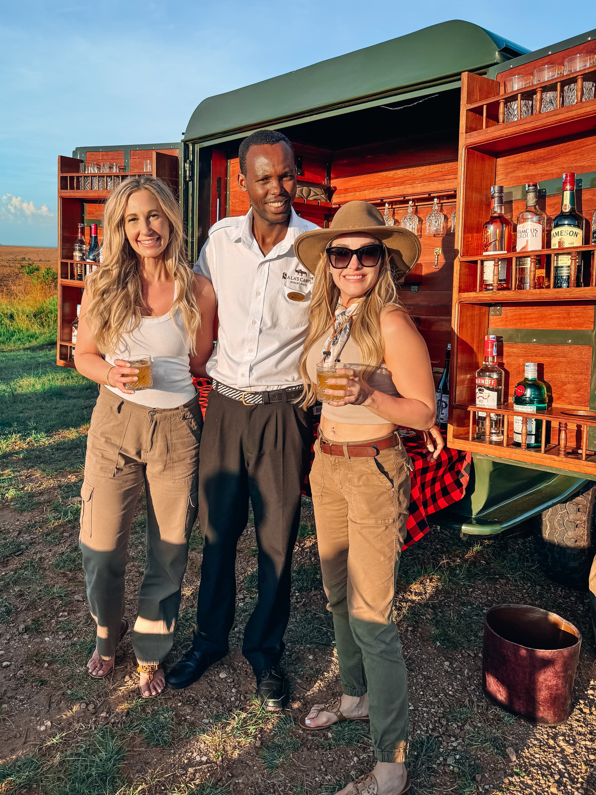 Three people posing in front of a truck with bar amenities outside.