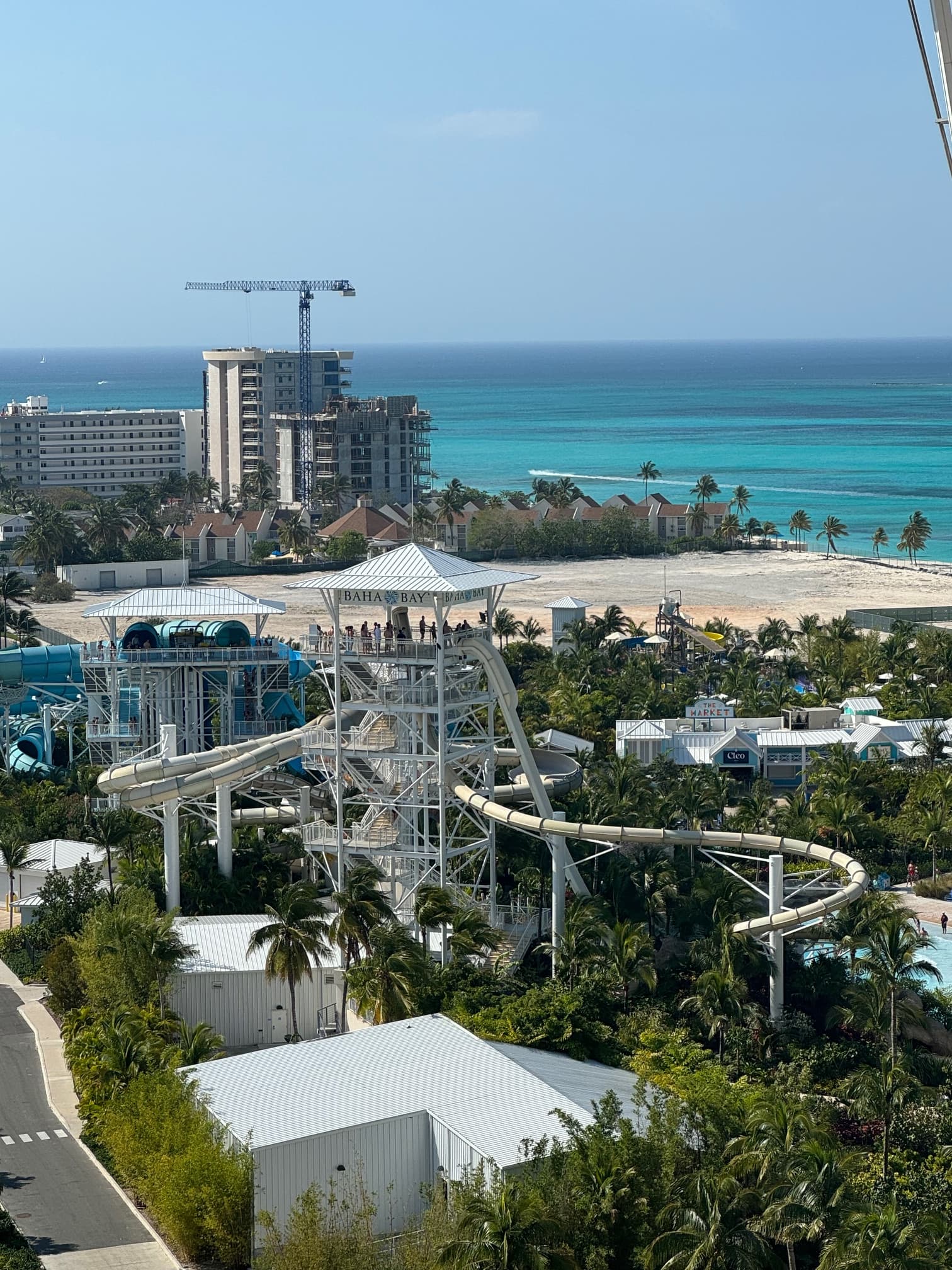 An aerial view of a waterpark with the turquoise ocean in the distance and various buildings and trees scattered around.