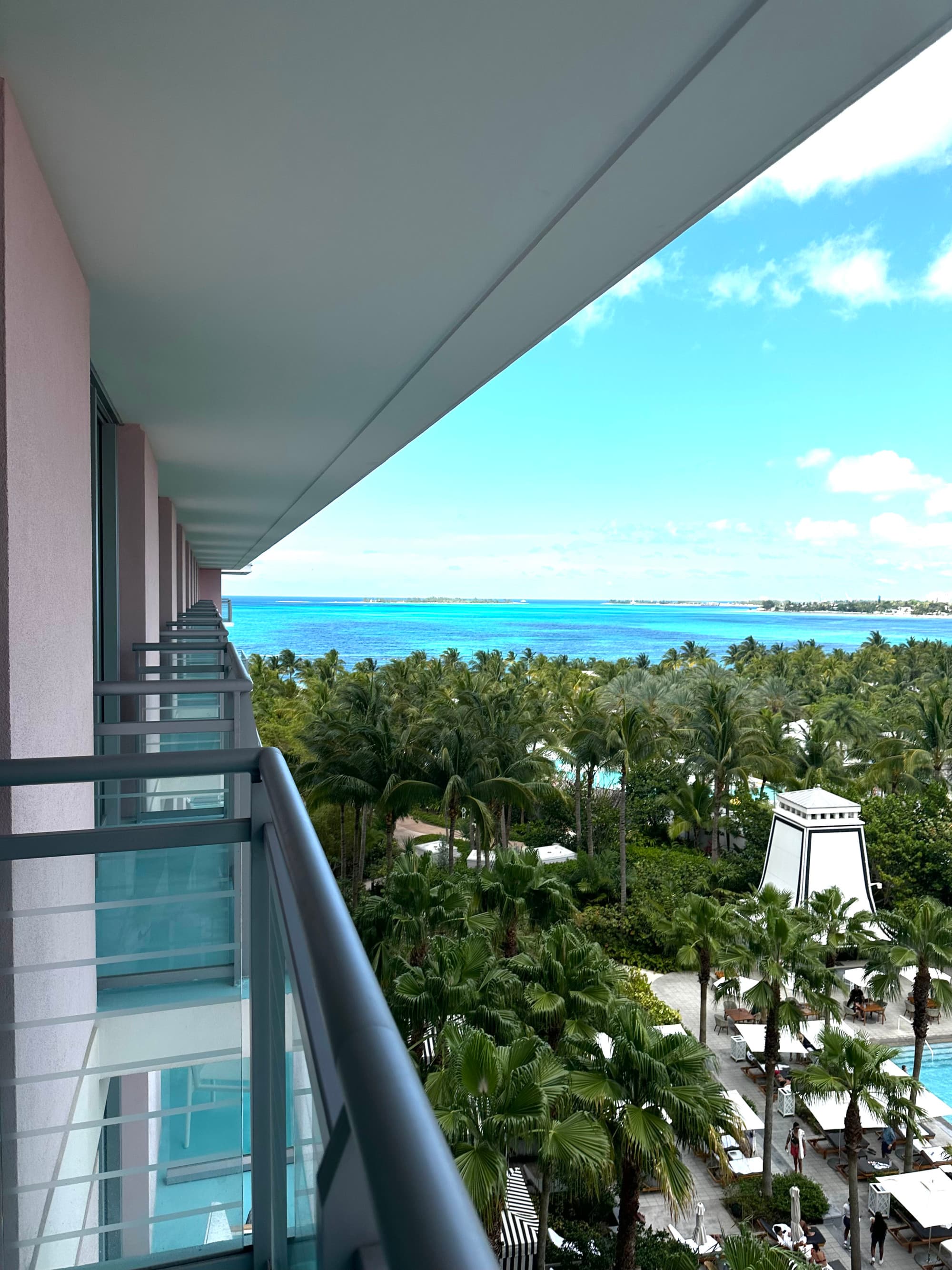A view of the hotel grounds decorated with palm trees, and the big blue sea and sky in the distance, from the hotel balcony.