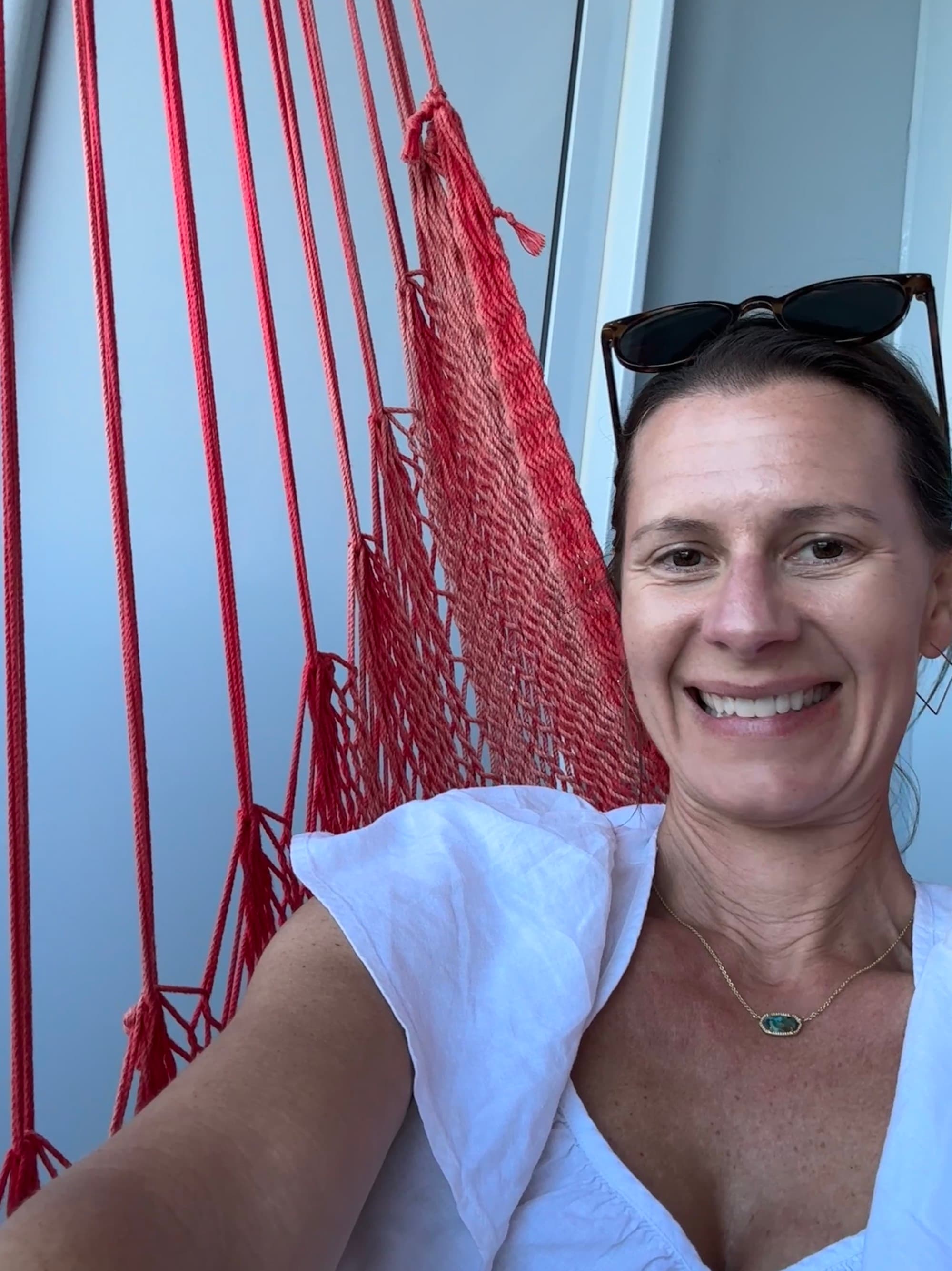 Travel advisor relaxing on a red, knitted hammock with a big smile on her face.