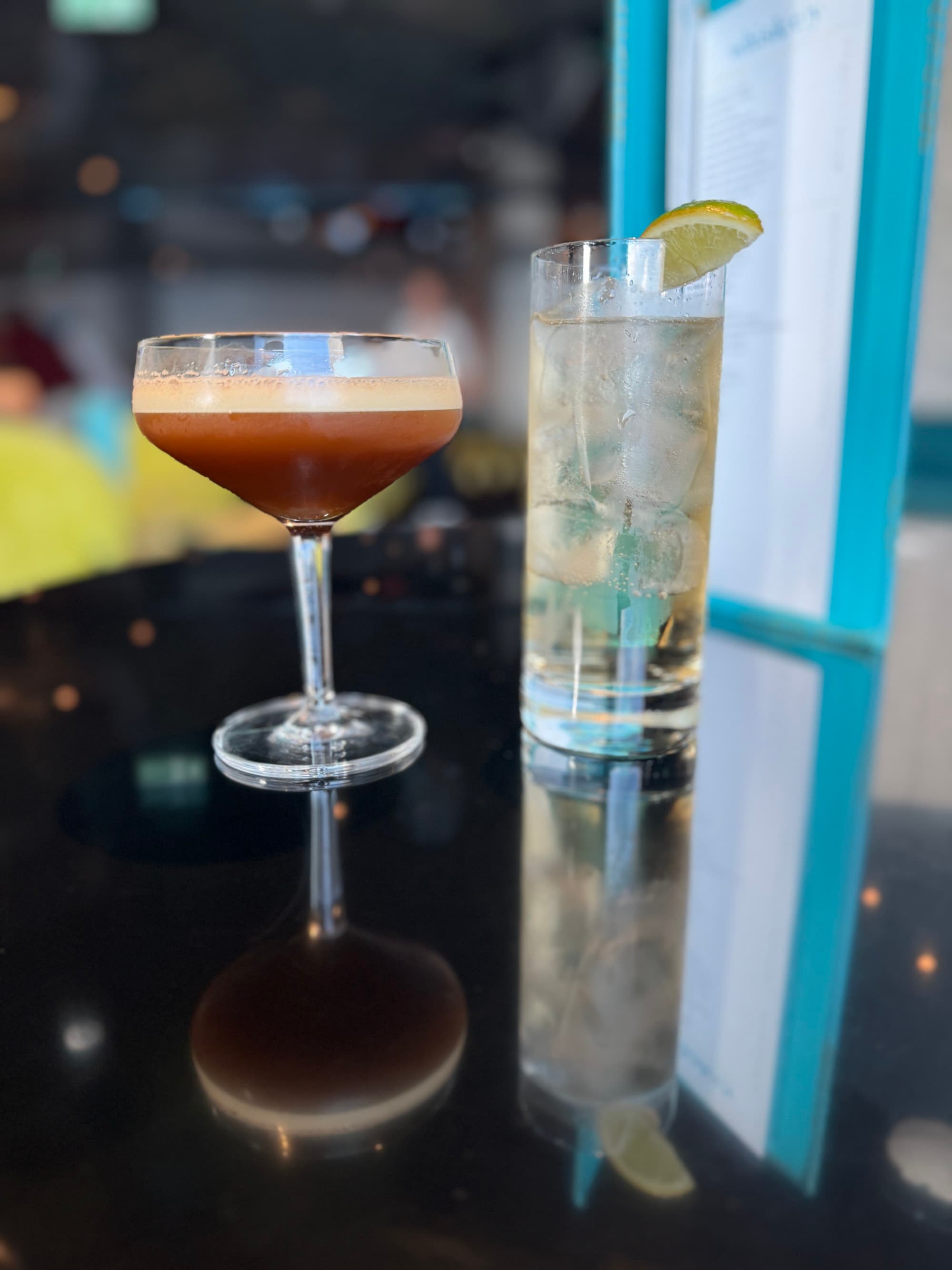 Cocktail hour with an espresso martini on the rocks, next to a tall glass of a clear-colored cocktail.