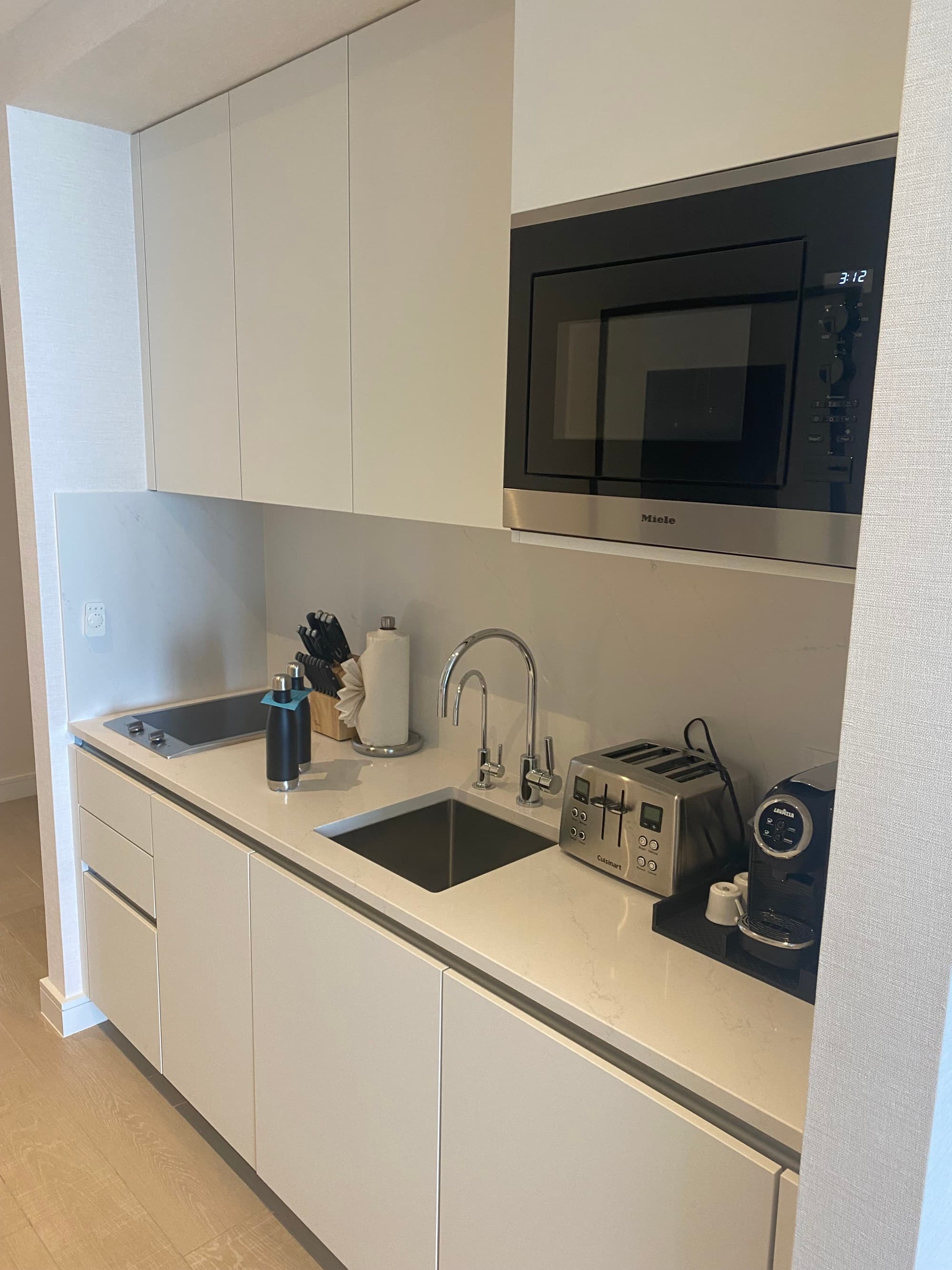 The hotel room kitchenette, with a sink, electric stove top, toaster, coffee maker and utensils.
