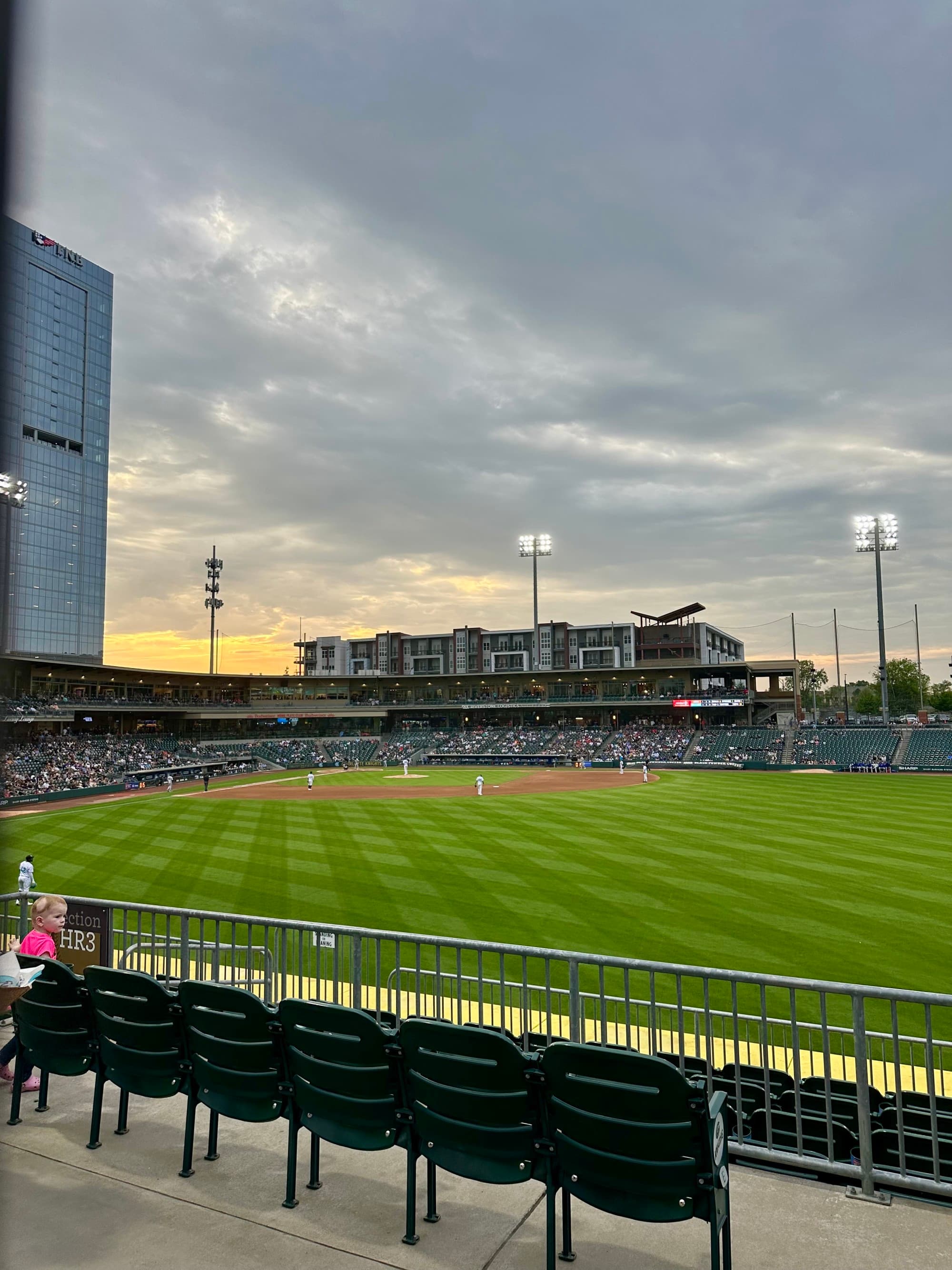 A baseball field and stadium of a game in-play, taken from the stands.