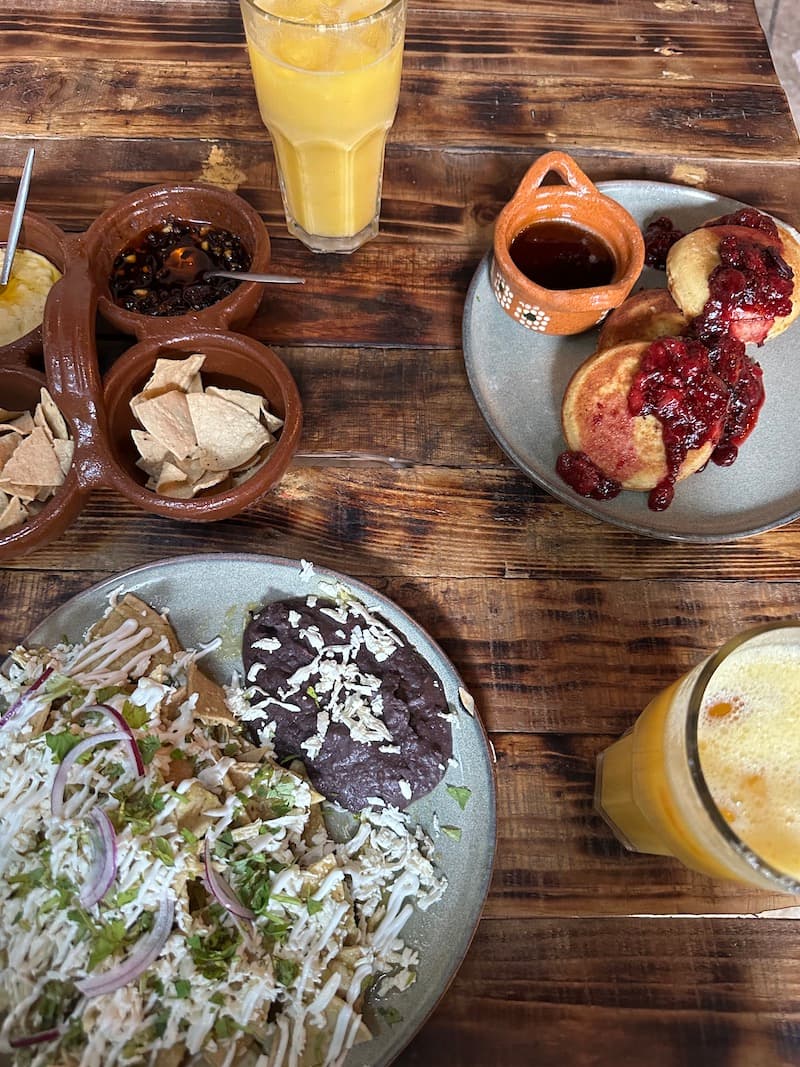 An overhead photo of plates of food and glasses of juice on a wooden table