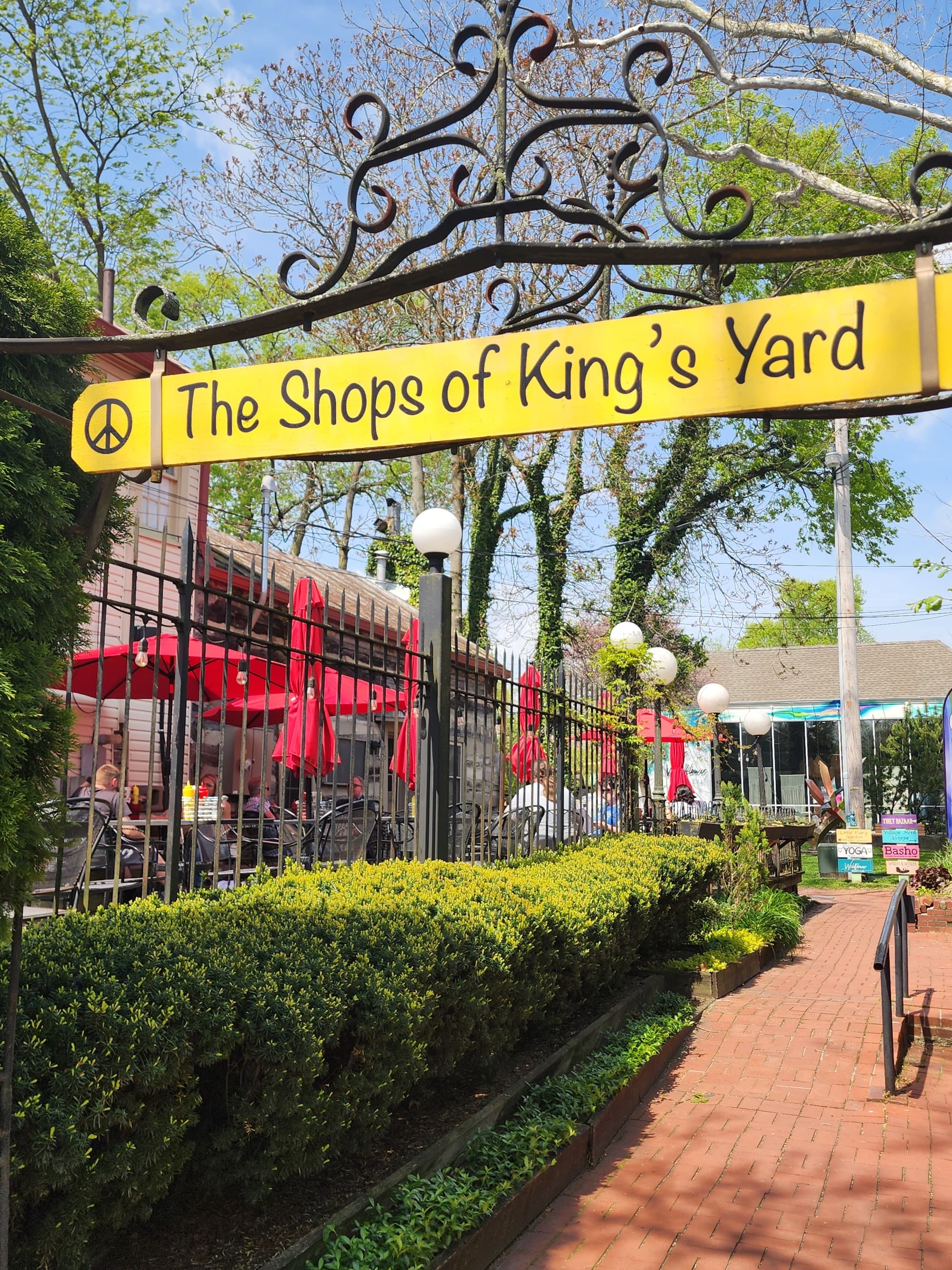 A yellow sign above a brick path reading "The Shops of King's Yard"