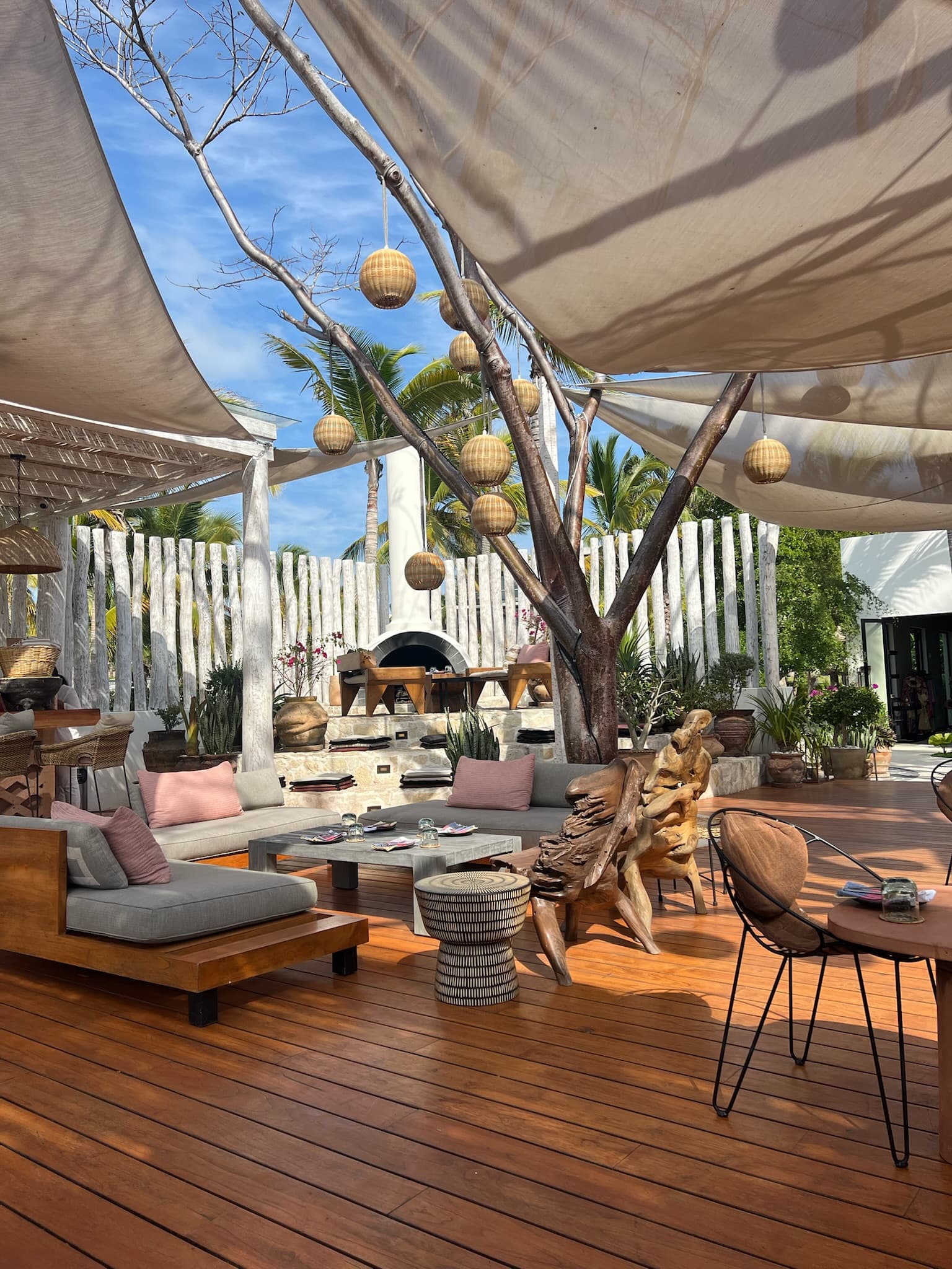 An outdoor lounge with hanging lanterns, awnings, cushioned chairs and sofas at La Boquita.